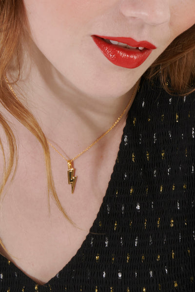  Scamp & Dude x Rachel Jackson Gold Plated Lightning Bolt Necklace with Black Pavé Detailing | Product image of gold lightning bolt necklace around woman's neck