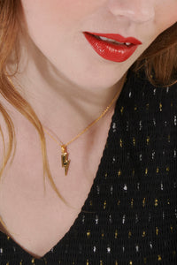 Scamp & Dude x Rachel Jackson Gold Plated Lightning Bolt Necklace with Black Pavé Detailing | Product image of gold lightning bolt necklace around woman&