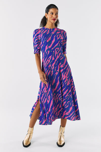 Scamp and Dude Pink with Blue and Green Shadow Tiger V-Back Midi Dress | Model wearing bright pink and blue zebra print dress with slit in the leg with short gold boots