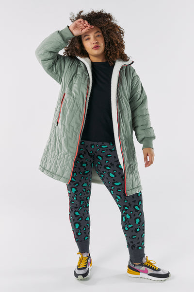 Scamp and Dude Adults Reversible Quilted Coat Khaki Lightning Bolt | Model wearing khaki coat with leopard print leggings against white background