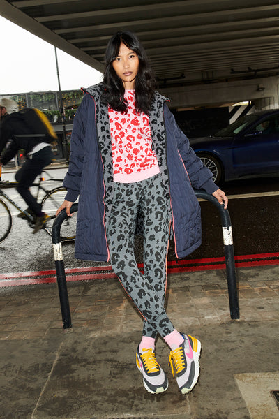Scamp and Dude Reversible Quilted Navy Lightning Bolt and Grey with Black Leopard Borg Coat | Model photographed on the side of the street wearing grey leopard print leggings and pink leopard jumper with reversible navy and grey coat