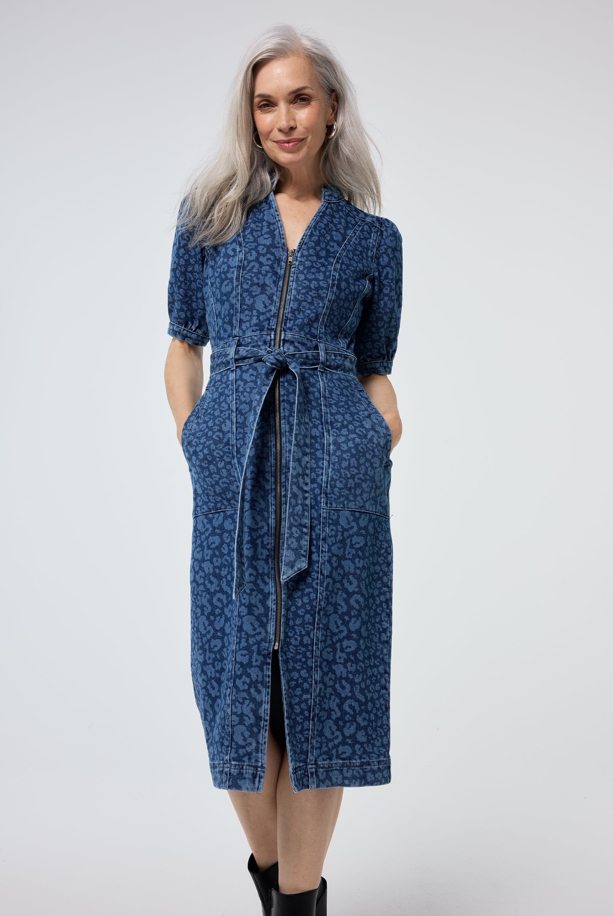 Scamp and Dude Authentic Indigo Leopard Zip Detail Denim Dress | Model wearing a leopard print blue denim dress with a zip front and tie waist, paired with black boots.