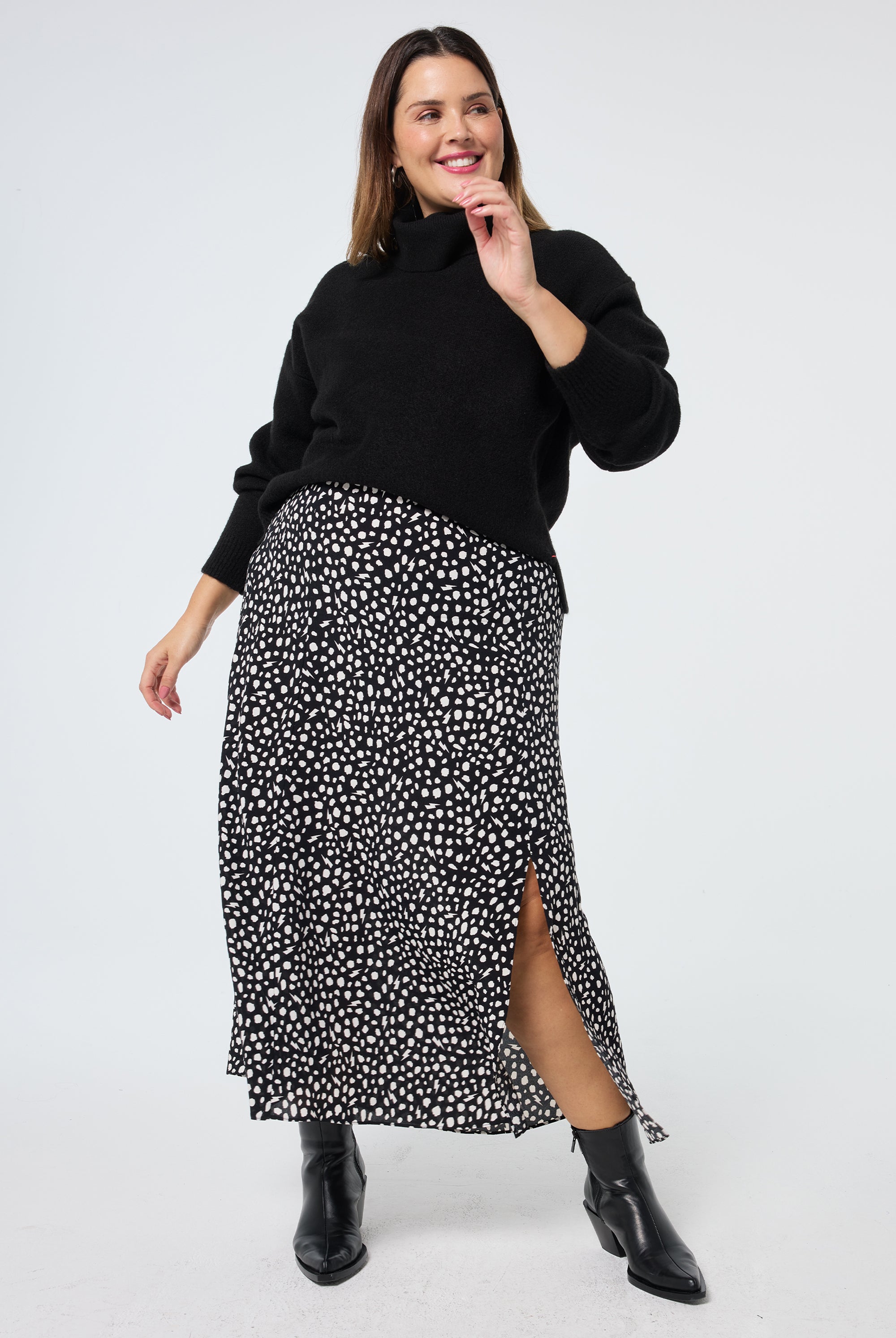 Scamp and Dude Black with White Cheetah Side Split Skirt | Model wearing a black turtle neck jumper with a black and white cheetah print skirt.