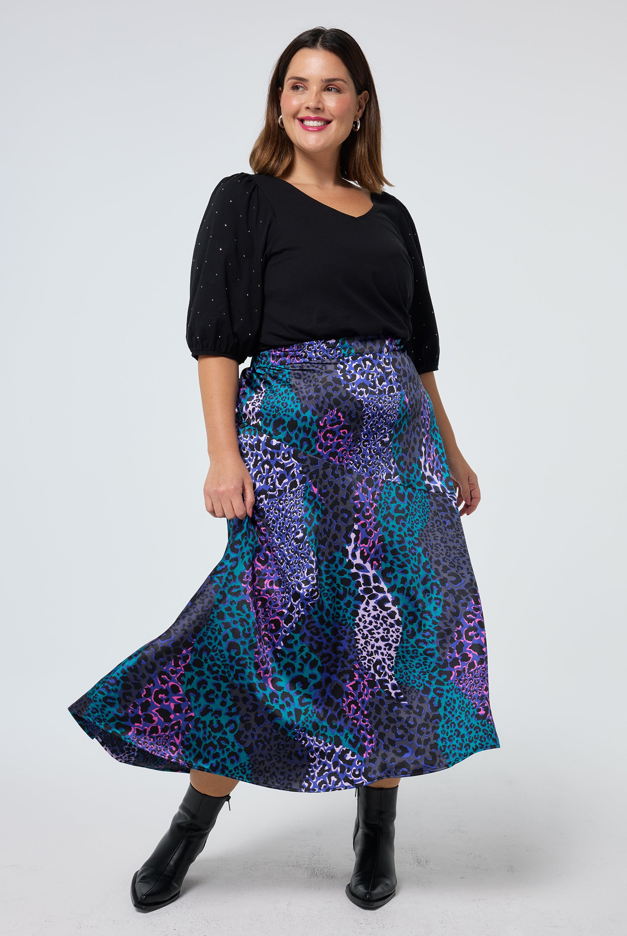 Scamp and Dude Blue with Green Spliced Leopard Satin High Low Hem Skirt | Model wearing a black v neck t shirt with a blue spliced high low hem skirt.