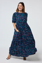 Scamp and Dude Teal with Rainbow Shadow Leopard Maxi Dress | Model wearing a teal short sleeve tiered maxi dress with rainbow shadow leopard print.