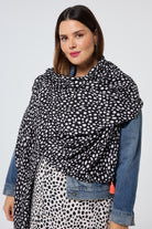 Scamp and Dude Black with White Cheetah Charity Super Scarf | Model wearing a cheetah print dress with a denim jacket and a matching scarf.