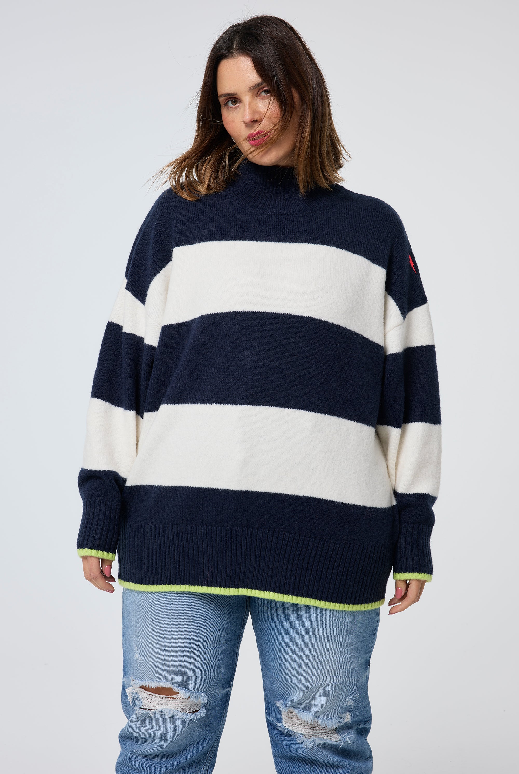 Scamp and Dude Navy with Ivory Stripe Oversized Turtle Neck Jumper | Model wearing a navy and ivory stripe turtleneck jumper paired with distressed jeans.