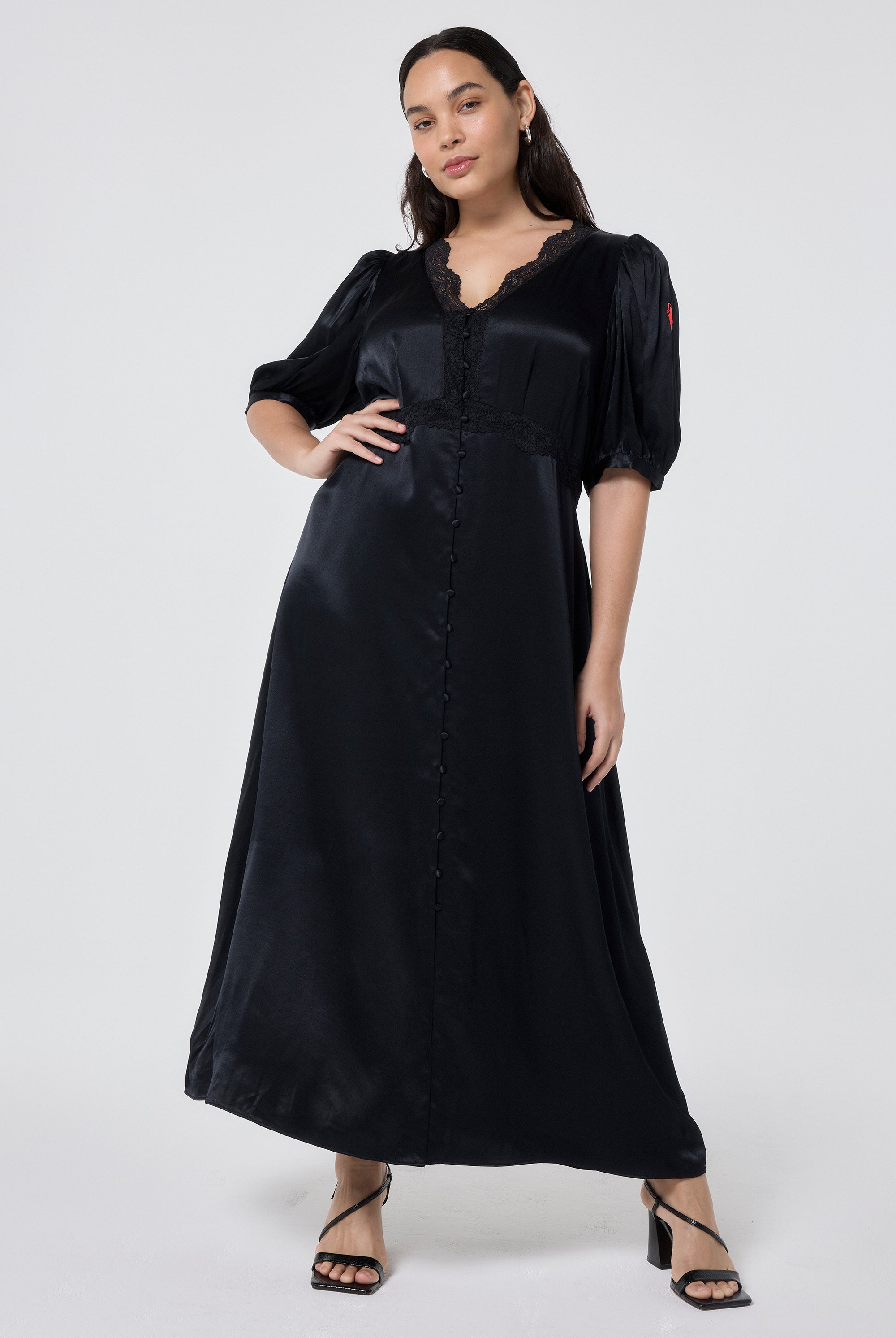 Scamp and Dude Black with Lace Trim Satin Puff Sleeve Midi Tea Dress | Model wearing a black satin midi tea dress featuring lace trim detail paired with black heels.