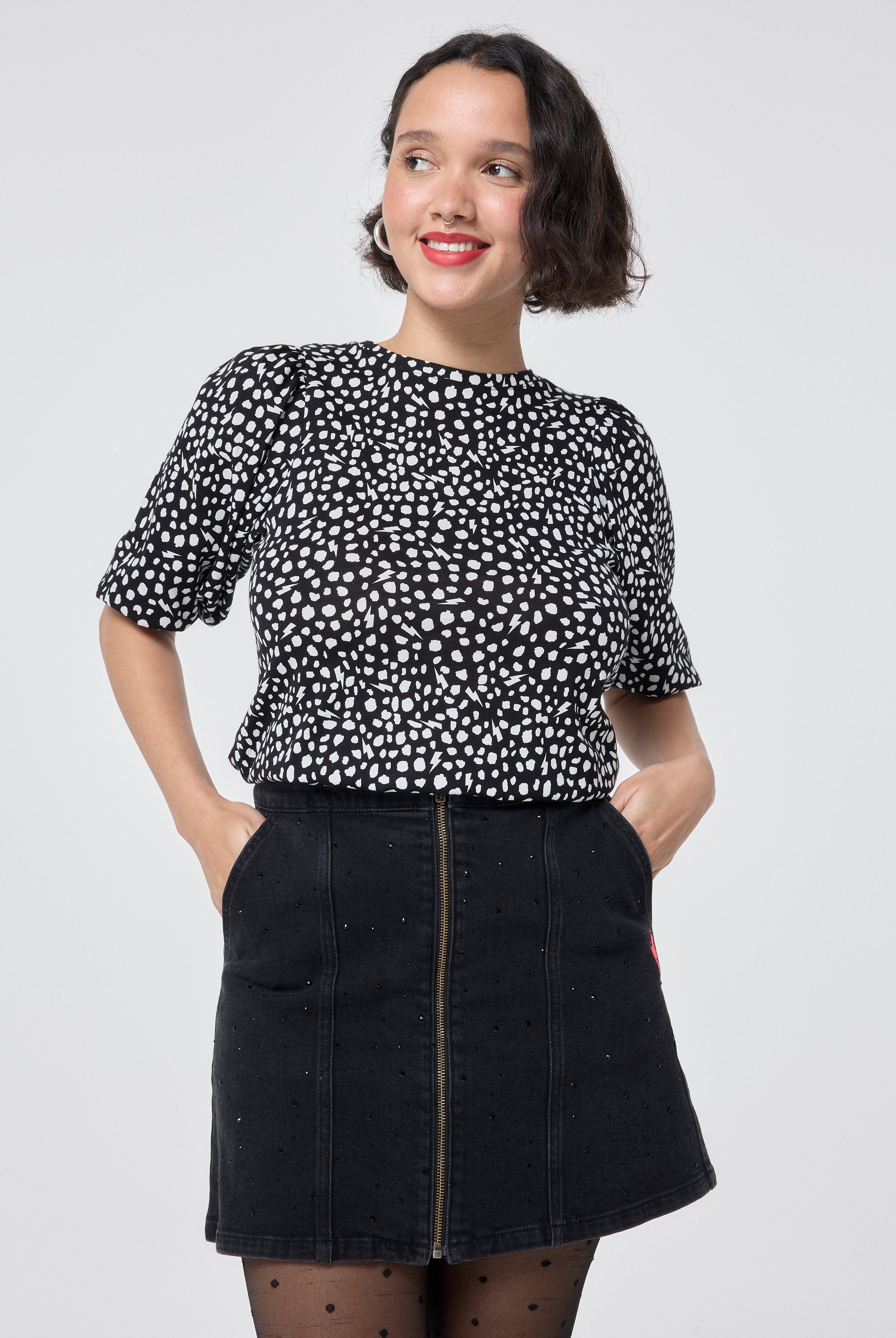 Scamp and Dude Black with White Cheetah Puff Sleeve T-Shirt | Model wearing a black t shirt with white cheetah print, paired with a black denim mini skirt and black tights.