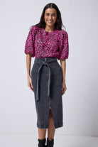Scamp and Dude Washed Black Zip Detail Denim Midi Skirt | Model wearing a pink leopard puff sleeve t shirt with a black denim skirt and black boots.