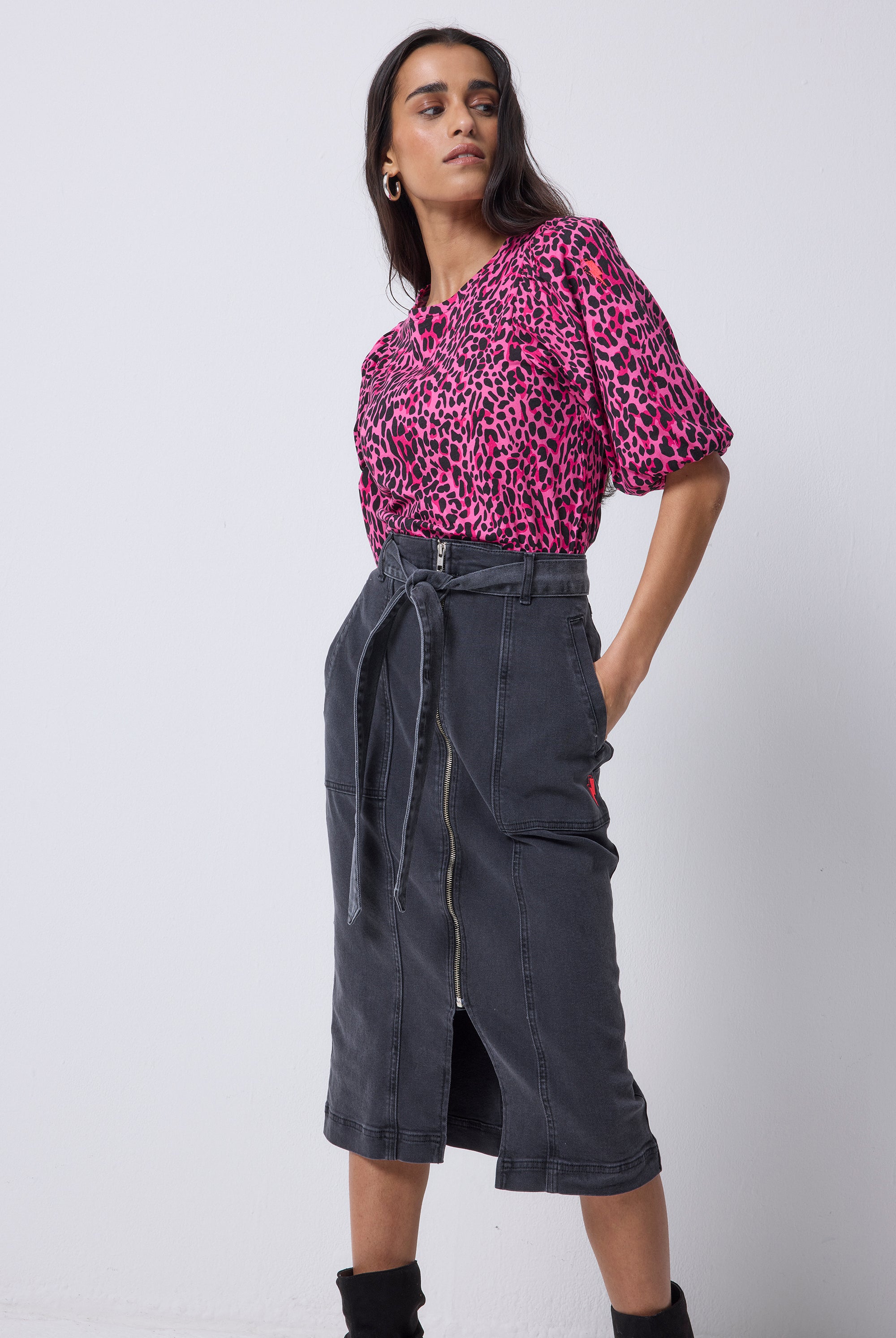 Scamp and Dude Washed Black Zip Detail Denim Midi Skirt | Model wearing a pink leopard puff sleeve t shirt with a black denim skirt and black boots.