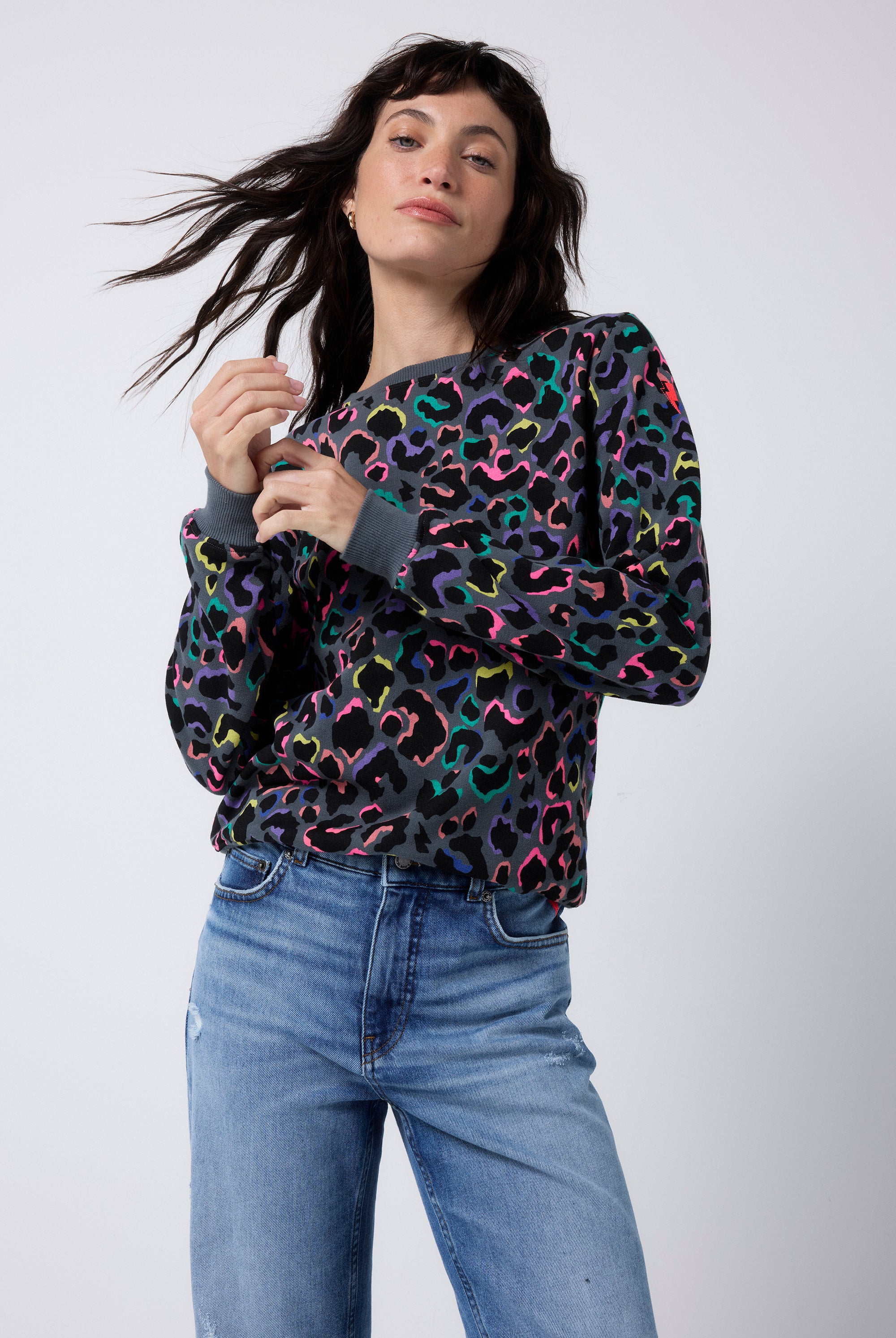 Scamp and Dude Grey with Rainbow Shadow Leopard Classic Sweatshirt | Model wearing a grey crew neck sweatshirt in a classic fit with rainbow shadow leopard print, paired with blue distressed jeans.