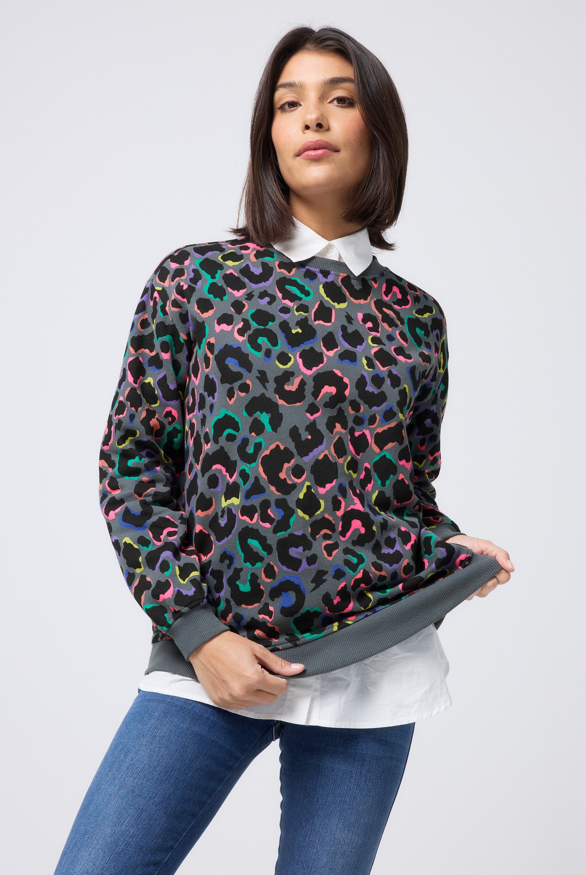 Scamp and Dude Grey with Rainbow Shadow Leopard Oversized Sweatshirt | Model wearing blue jeans with a grey and rainbow leopard print oversized jumper. Worn with a white shirt underneath.