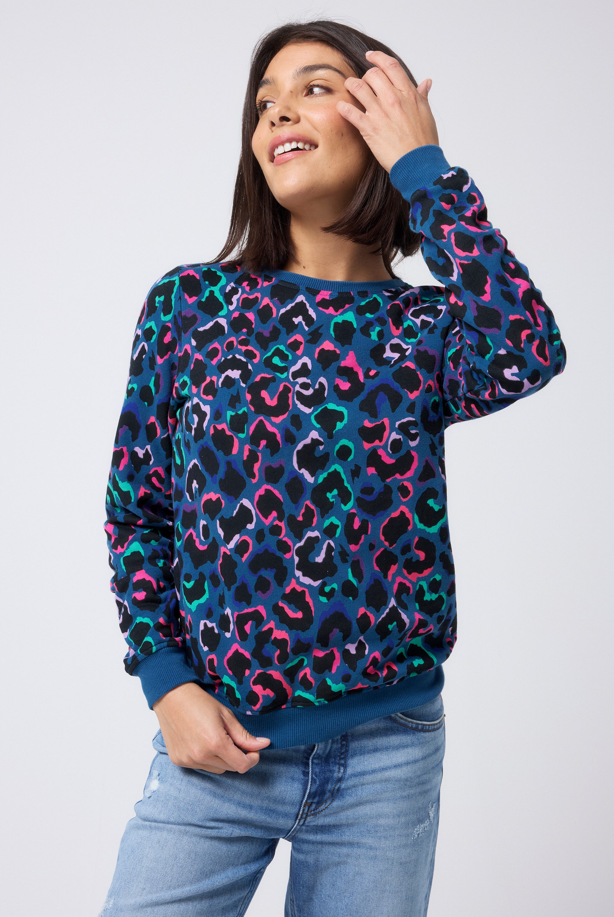 Scamp and Dude Teal with Rainbow Shadow Leopard Classic Sweatshirt | Model wearing a teal classic fit sweatshirt with rainbow shadow leopard print. Worn with blue distressed jeans.