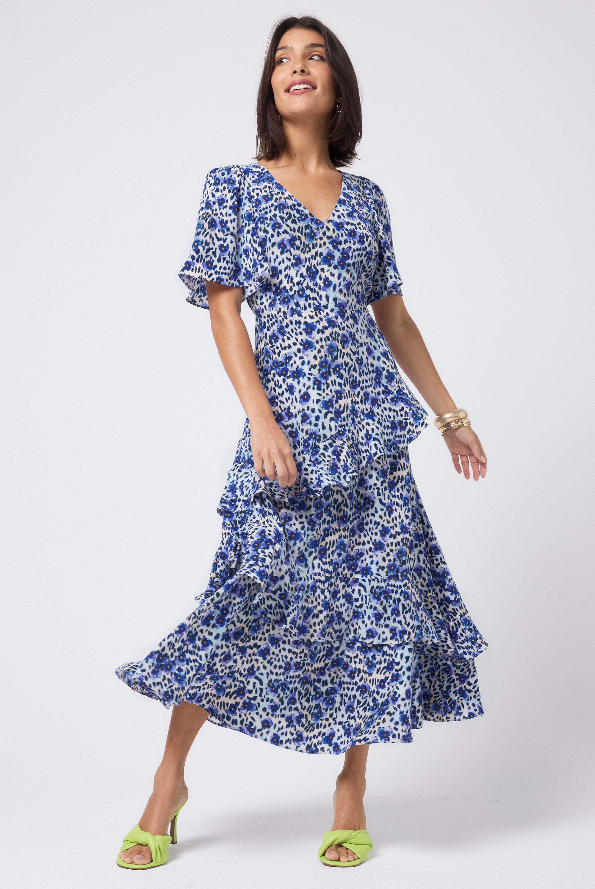 Scamp and Dude White with Blue Floral Animal Print Ruffle Detail Maxi Dress | Model wearing a white v-neck maxi dress with blue and black floral animal print. Worn with neon yellow heels.