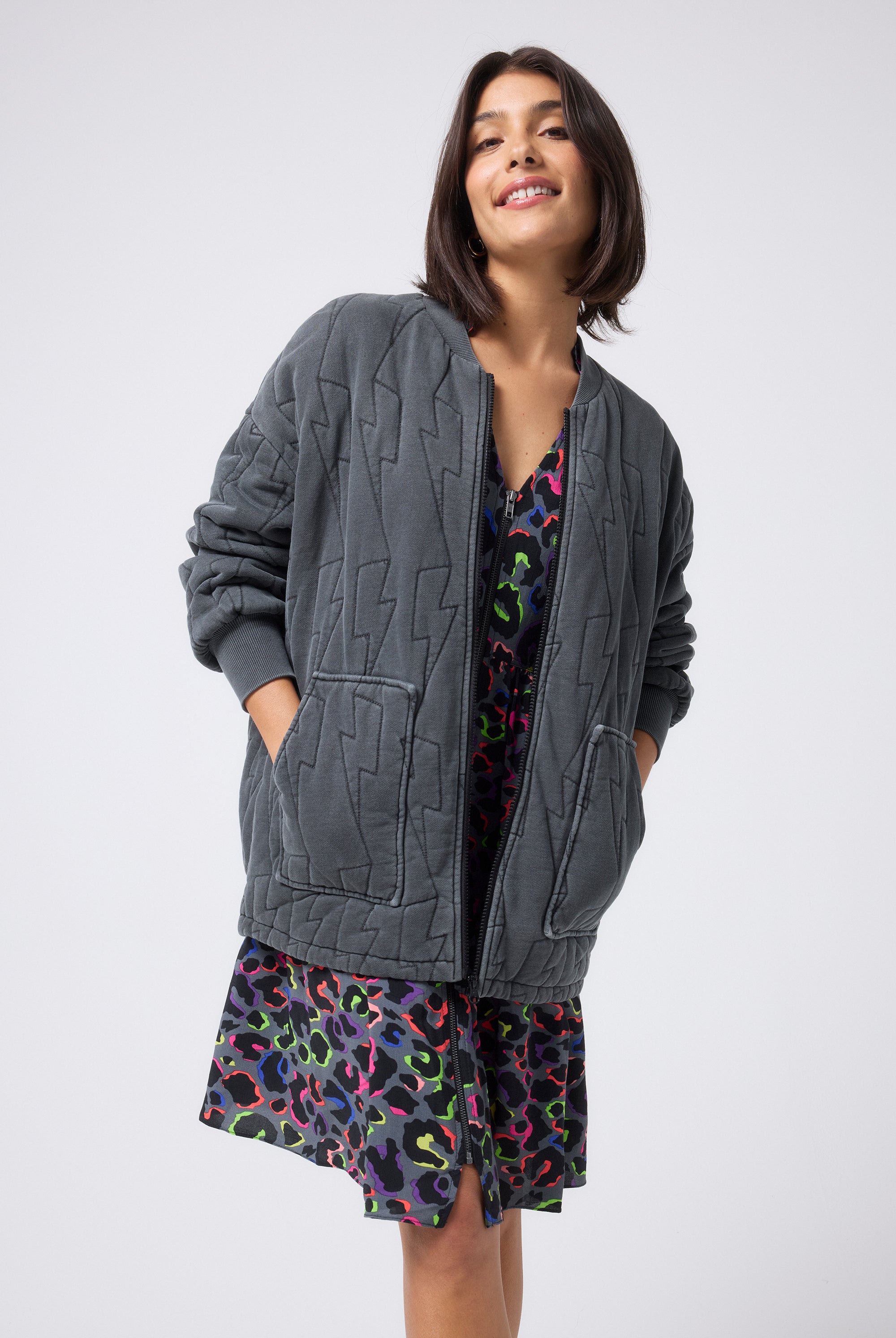 Scamp and Dude Washed Black Organic Cotton Quilted Lightning Bolt Oversized Bomber Jacket | Model wearing a grey rainbow leopard dress and washed black bomber jacket.