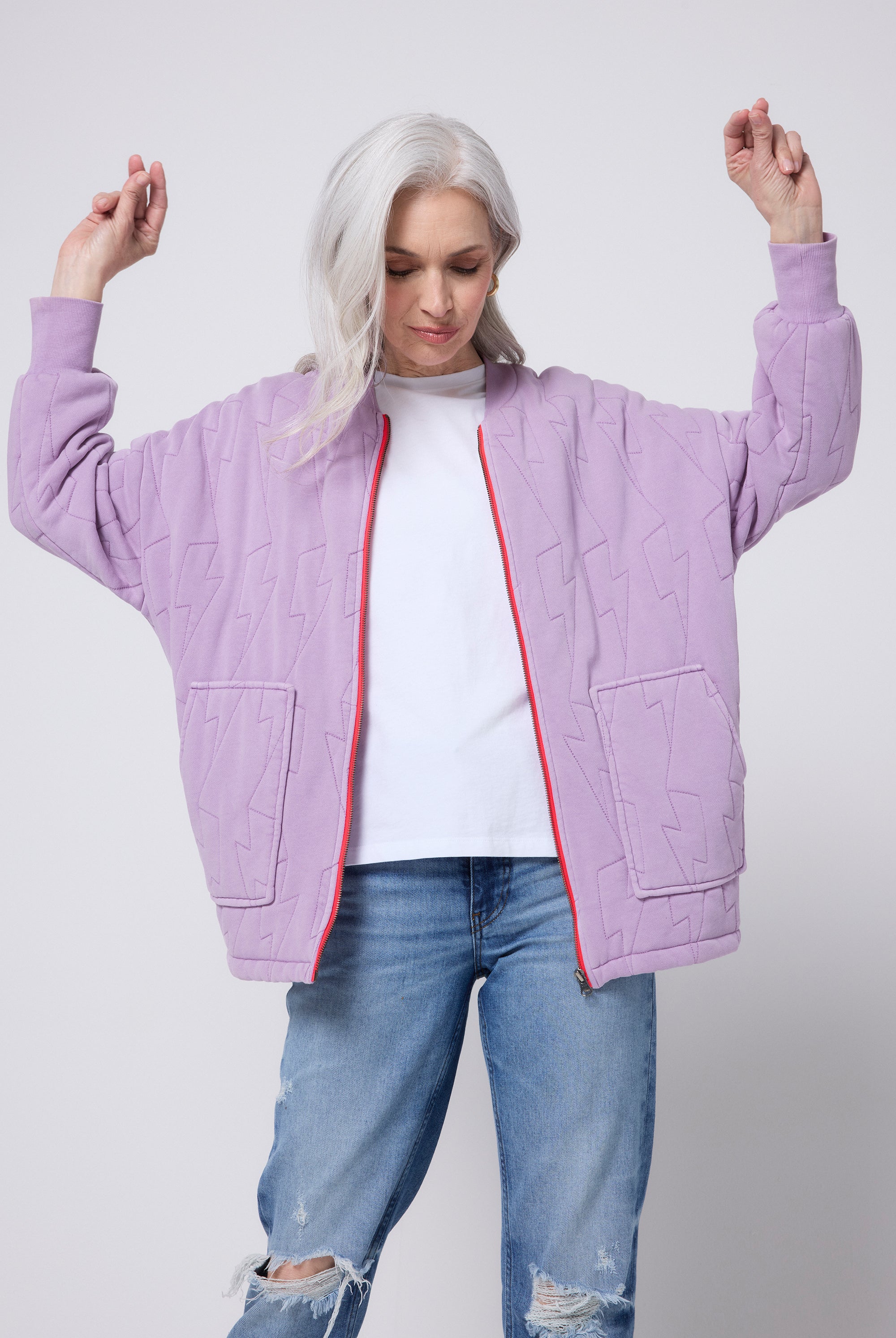 Scamp and Dude Lilac Organic Cotton Quilted Lightning Bolt Oversized Bomber Jacket | Model wearing a pair of distressed blue jeans with a white t-shirt and lilac bomber jacket.