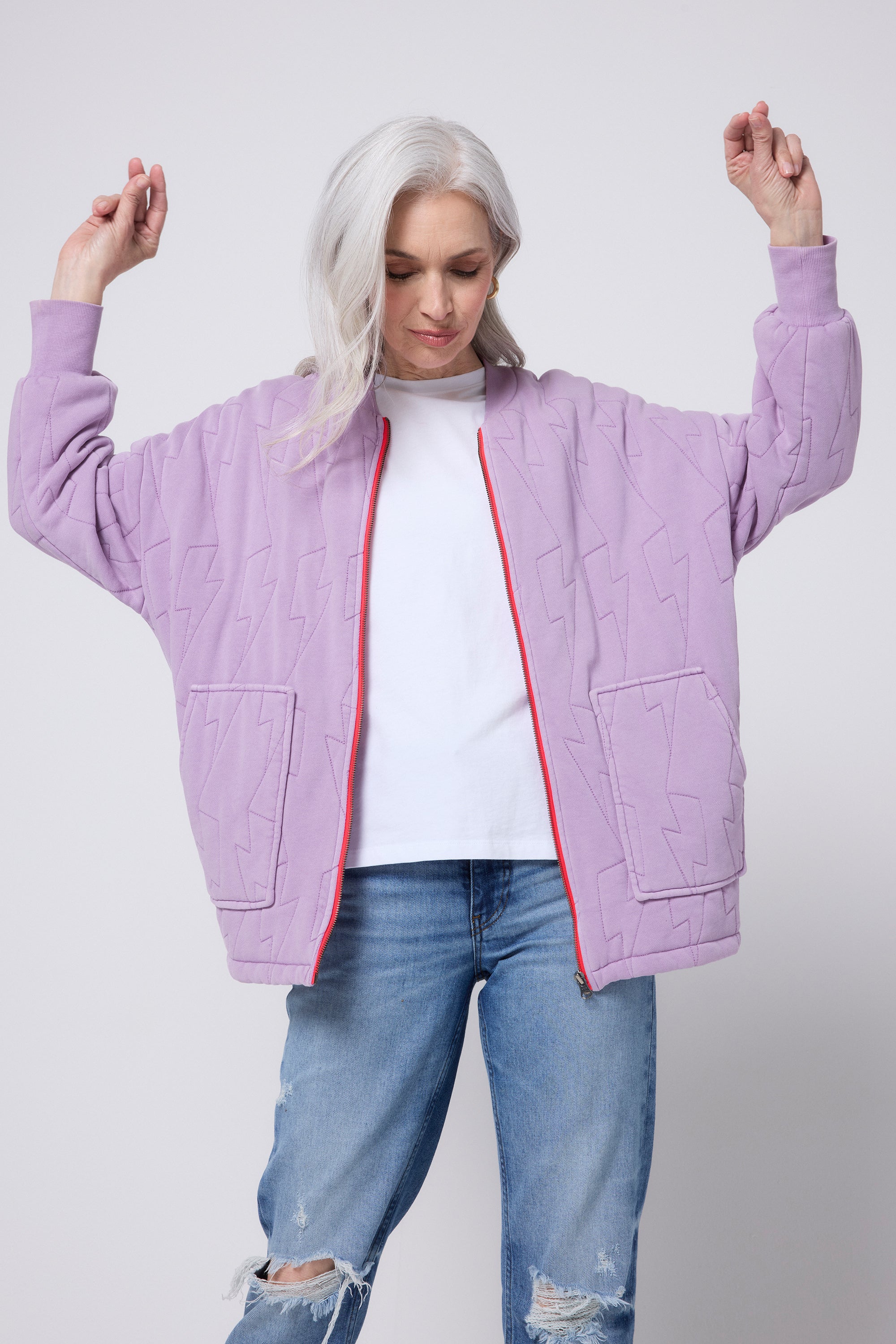 Scamp and Dude Lilac Organic Cotton Quilted Lightning Bolt Oversized Bomber Jacket | Model wearing a pair of distressed blue jeans with a white t-shirt and lilac bomber jacket.