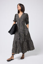 Scamp and Dude Khaki with Black Wild Leopard Zip Detail Tiered Midi Dress | Model wearing a short sleeve khaki zip front midi dress with black sandals and a black bag.