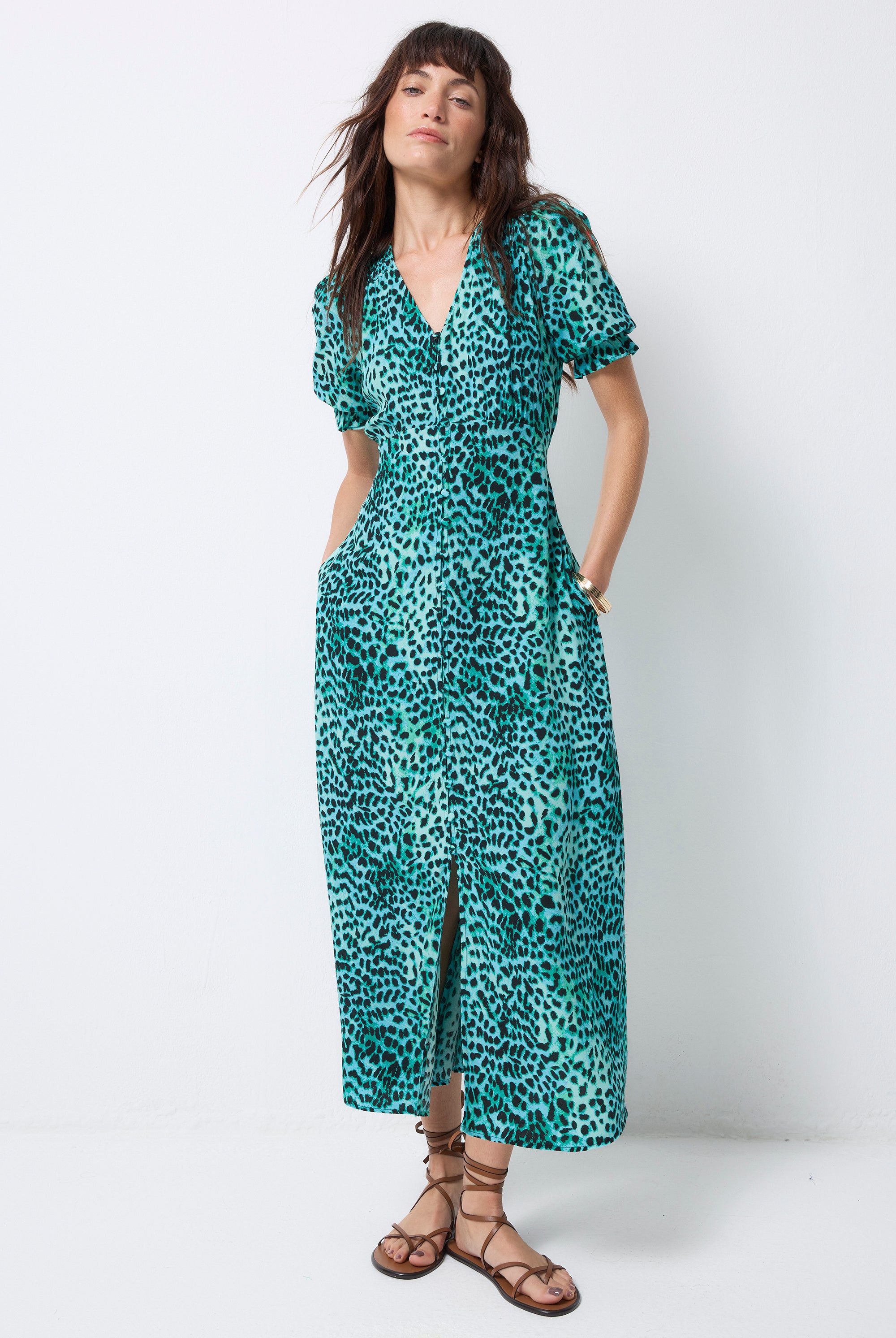 Scamp and Dude Turquoise with Black Wild Leopard Flute Sleeve Midi Tea Dress | Model wearing a flute sleeve v-neck midi tea dress in turquoise with black leopard print and sandals.
