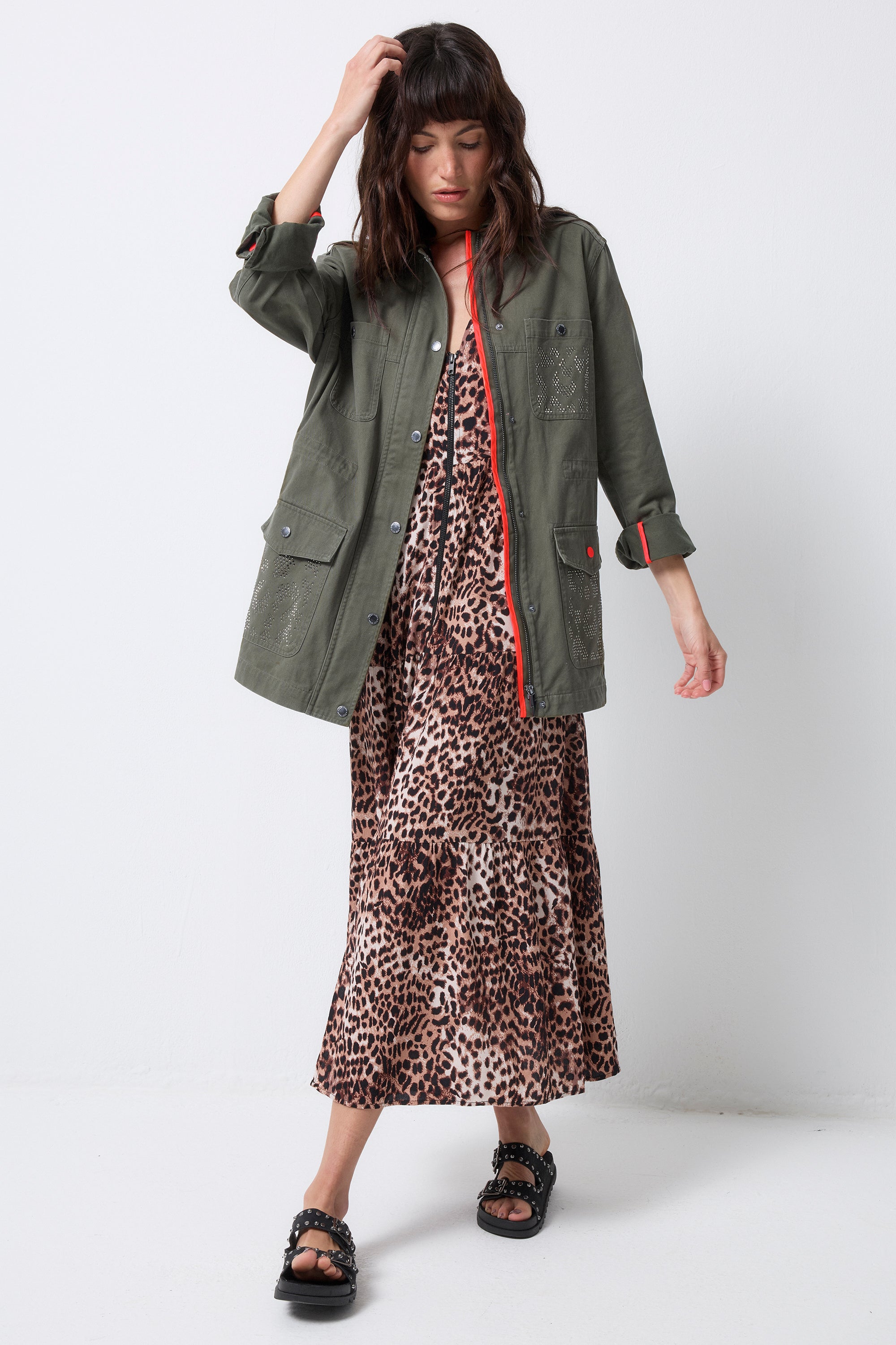 Scamp and Dude Khaki with Studded Bolt Utility Jacket | Model wearing a neutral cheetah zip front midi dress with a khaki studded utility jacket and black sandals.