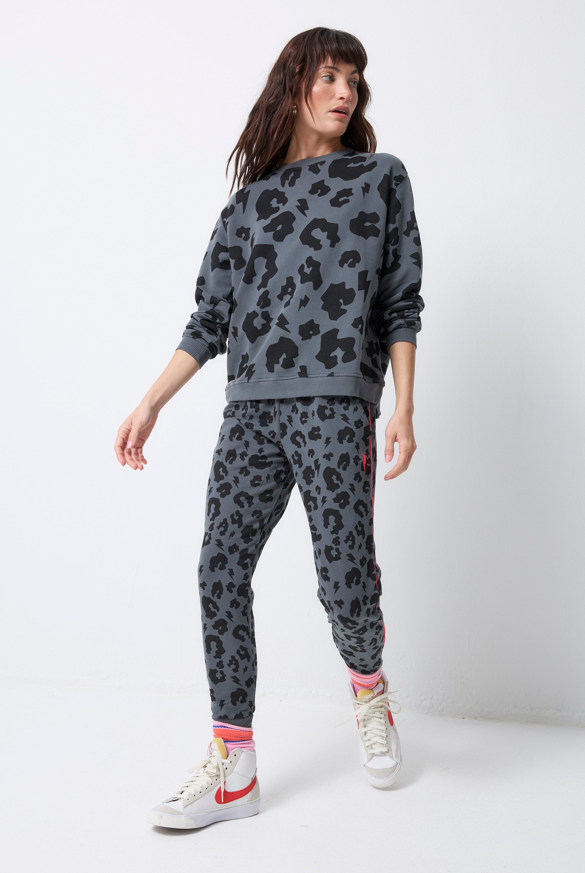 Scamp and Dude Grey Leopard Cosy Joggers | Model wearing a grey sweatshirt and grey joggers with black leopard print with neon coral piping detail.