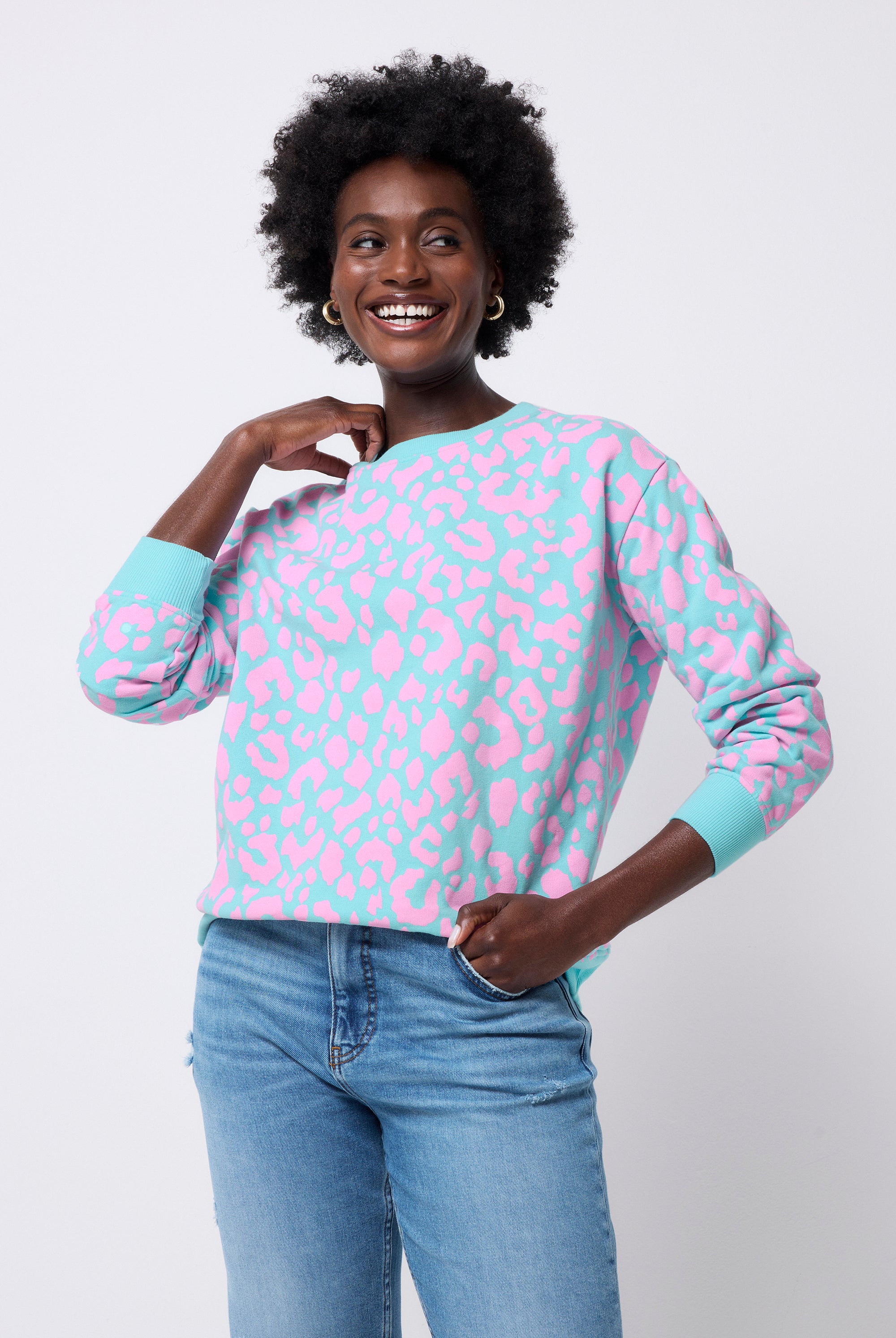 Scamp and Dude Turquoise with Pink Leopard Oversized Sweatshirt | Model wearing a turquoise sweatshirt with pink leopard and lightning bolt print. Worn with a pair of blue jeans.