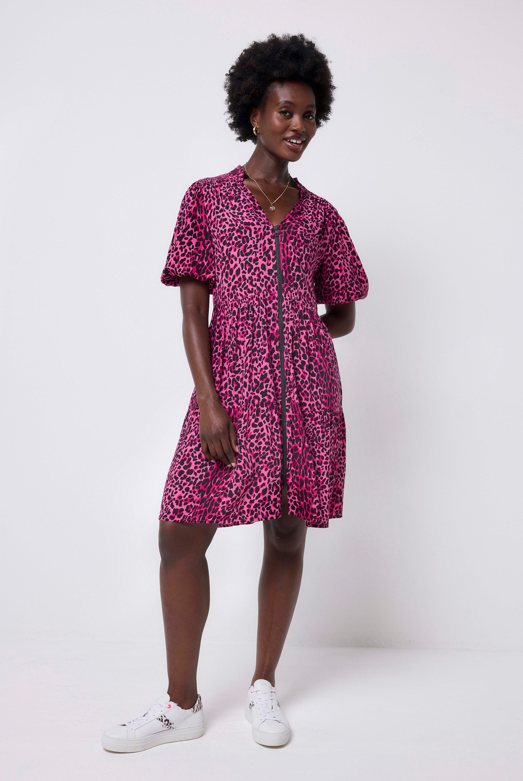 Scamp and Dude Pink with Black Wild Leopard Zip Detail Tiered Short Dress | Model wearing a pink puff sleeve dress in a wild leopard print with zip detail, paired with black tights and boots.