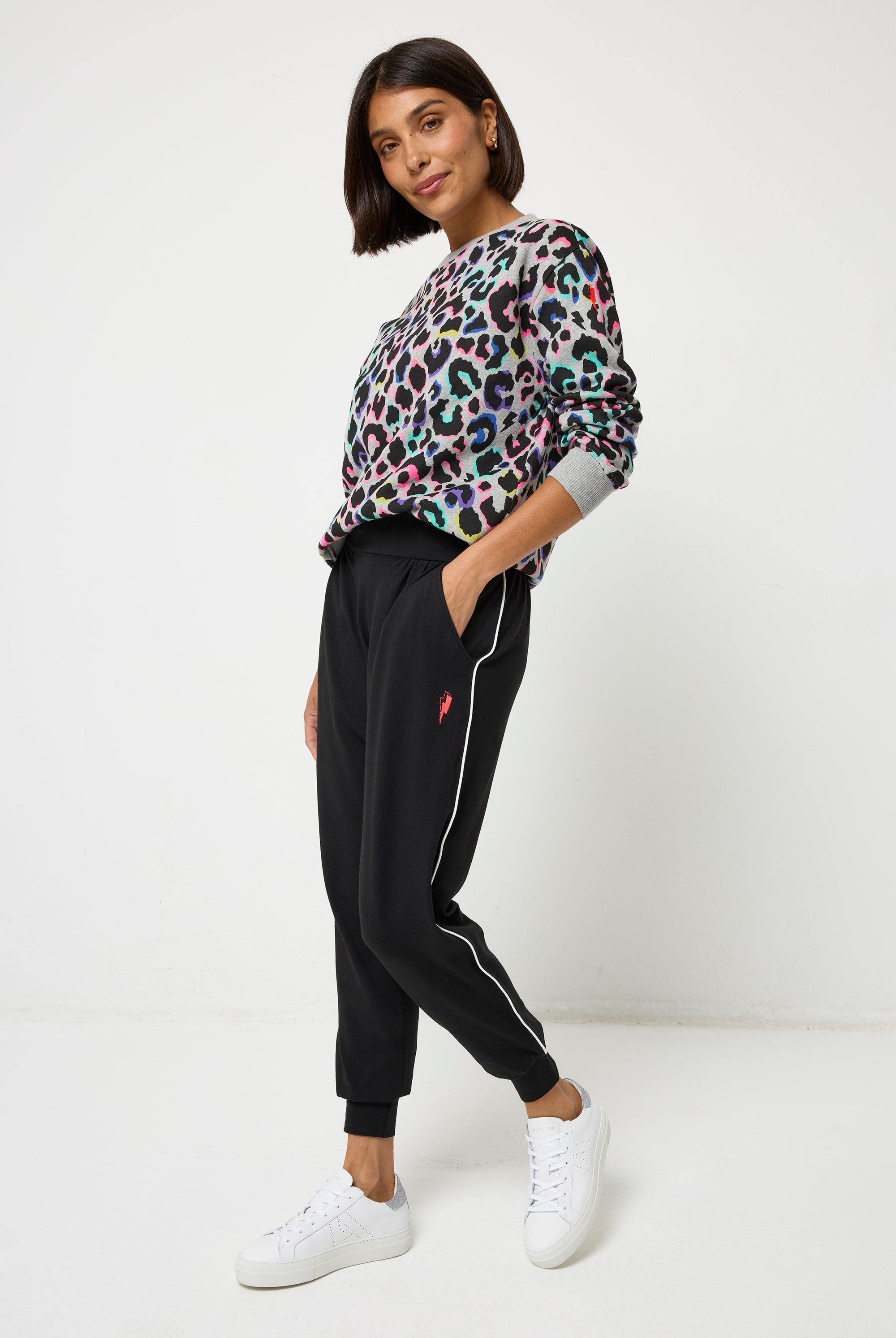 Scamp and Dude Black Slouch Jogger | Model wearing a crew neck grey rainbow leopard print sweatshirt with black joggers and white trainers.