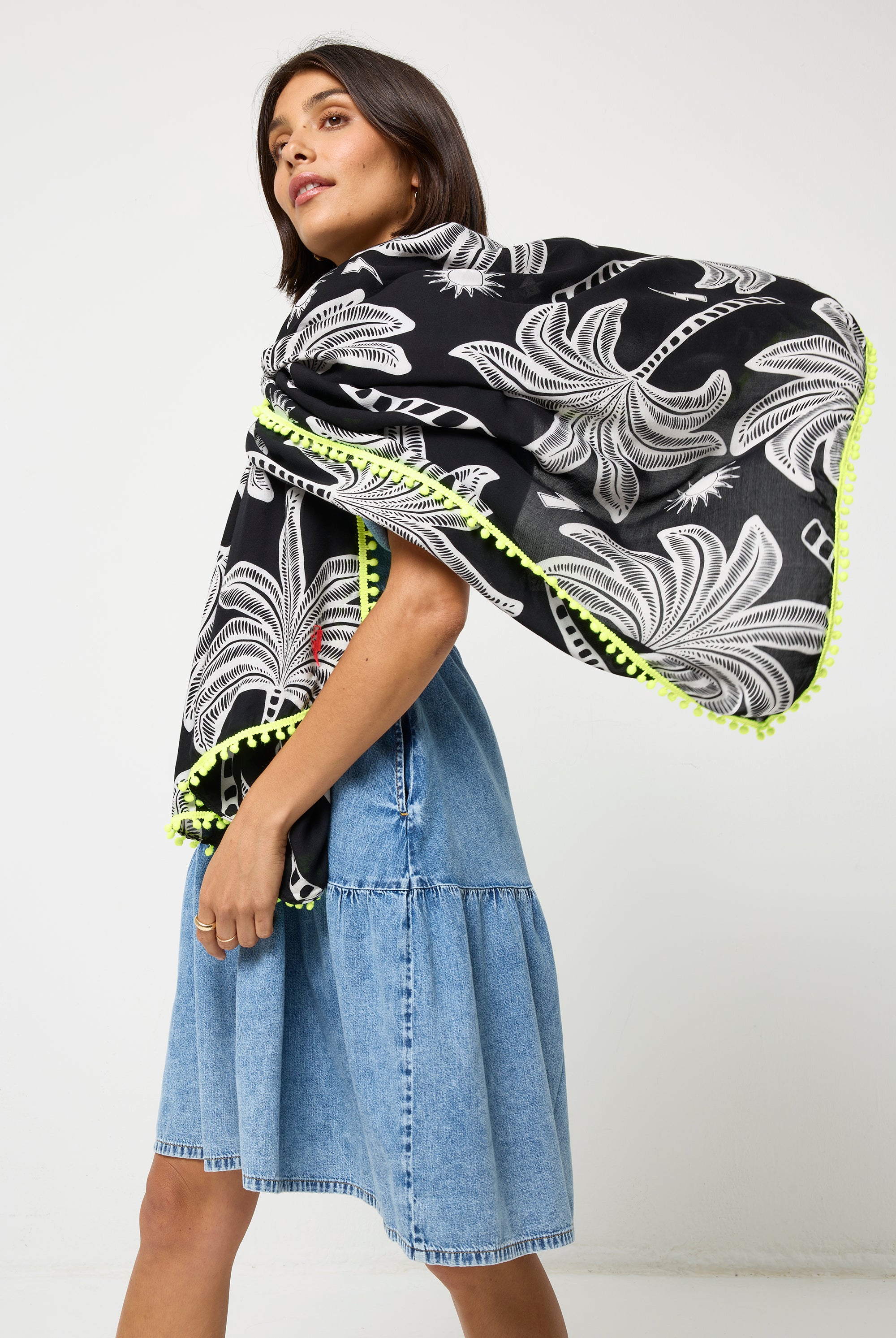 Scamp and Dude Black Palm Spring Charity Super Scarf  | Model wearing  a pale blue short denim dress with a black palm print super scarf.