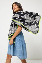 Scamp and Dude Black Palm Spring Charity Super Scarf  | Model wearing  a pale blue short denim dress with a black palm print super scarf.