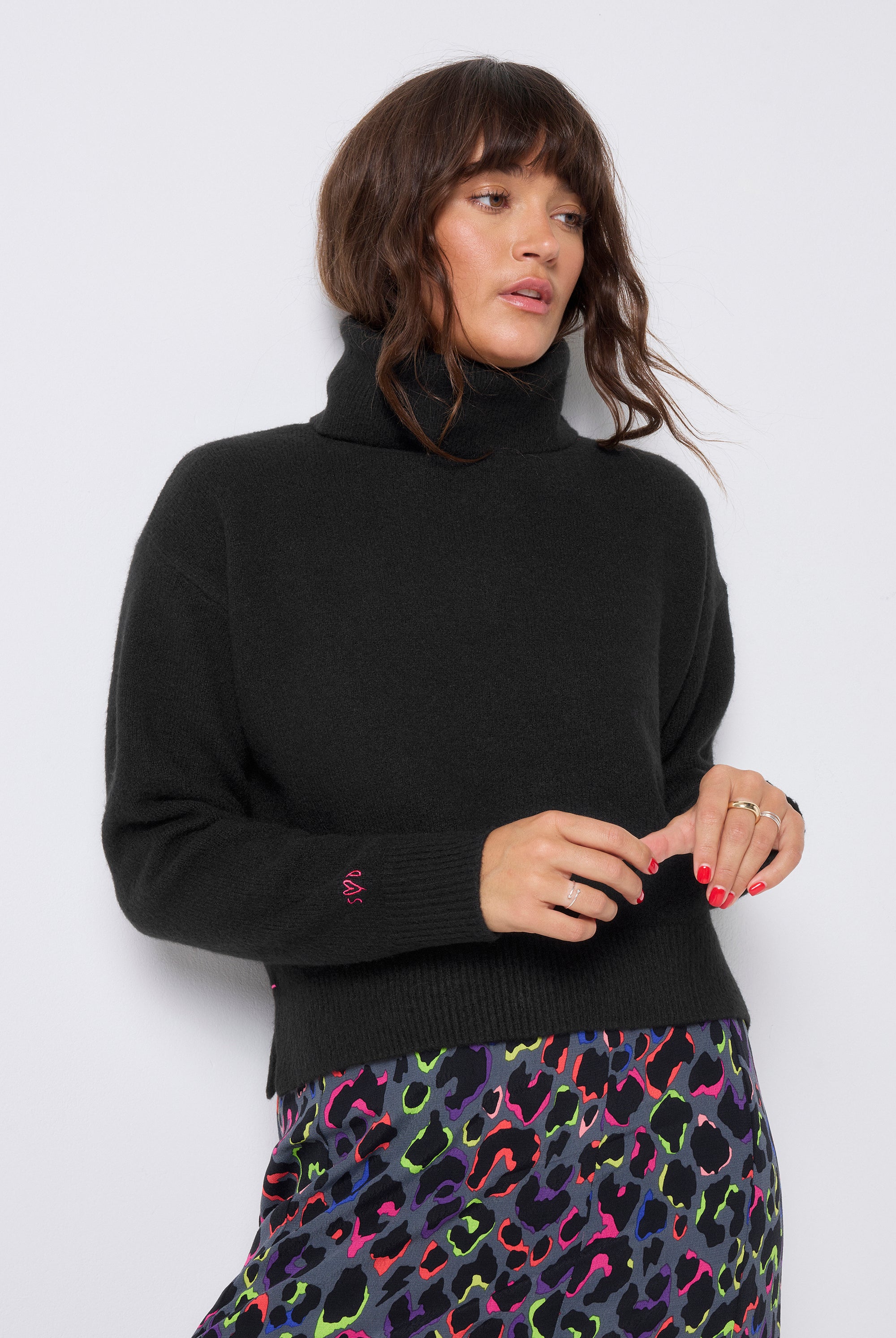 Scamp and Dude Black Turtleneck Knitted Jumper | Model wearing black turtleneck jumper with a grey rainbow leopard print skirt.