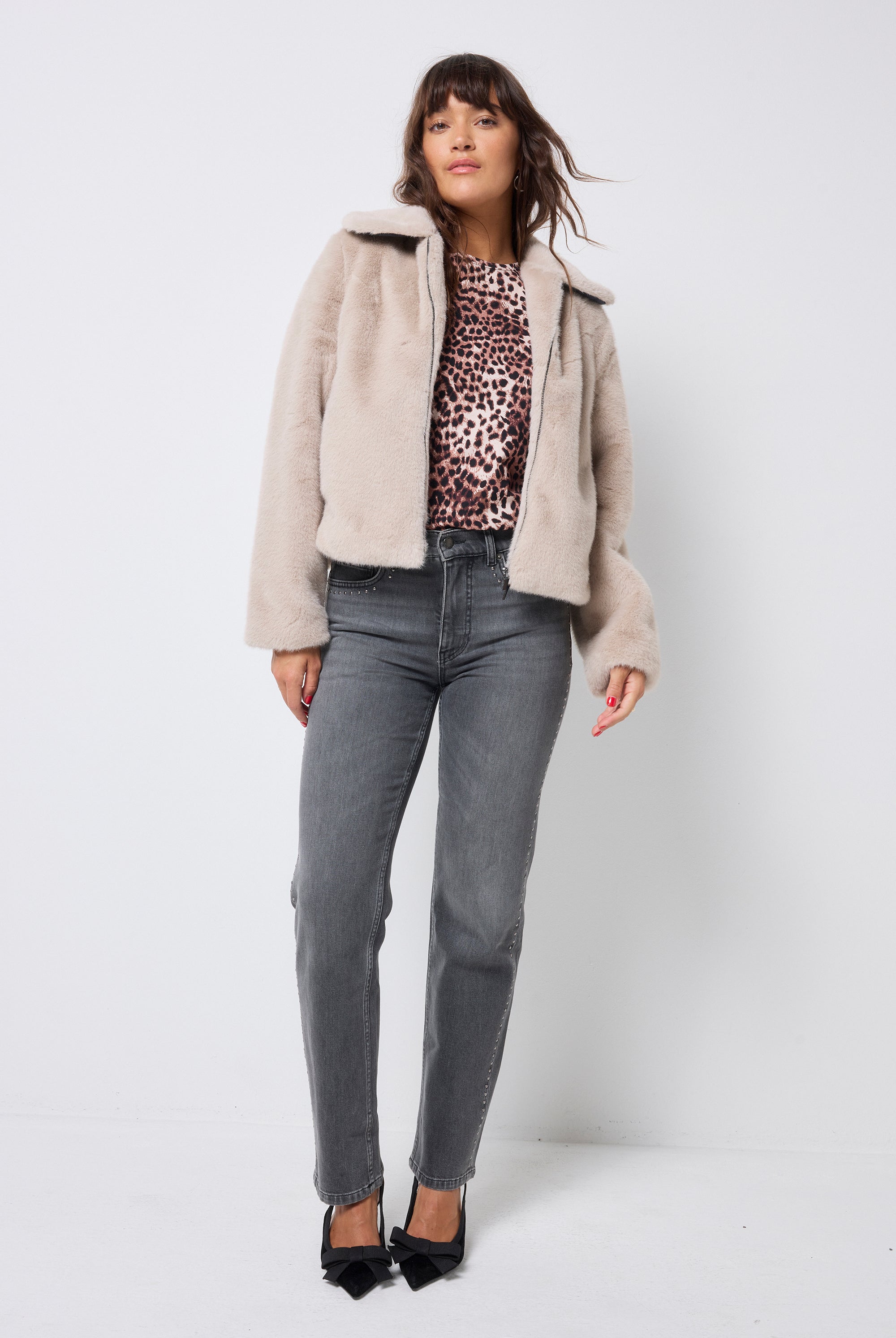 Scamp and Dude Cream Faux Fur Jacket | Model wearing washed black jeans with a faux fur jacket and neutral cheetah print top.