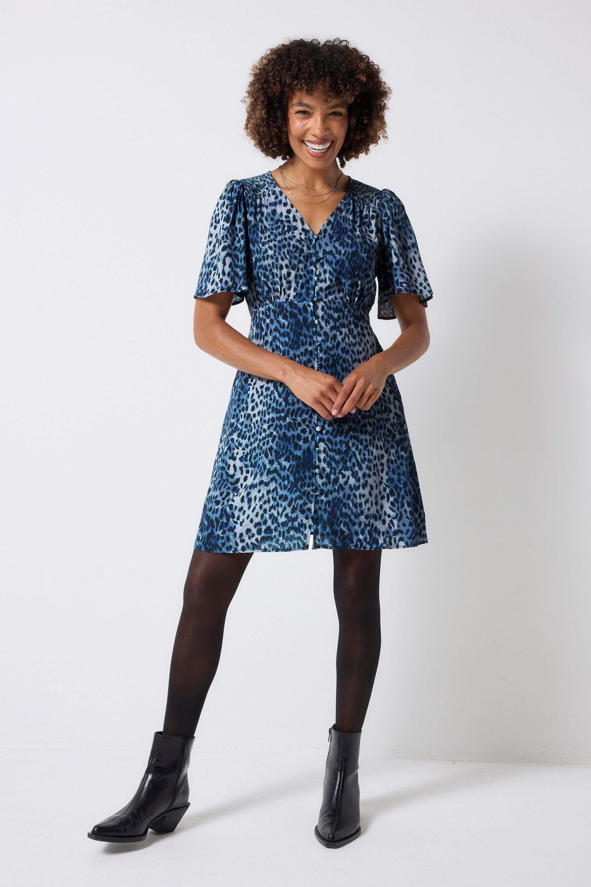 Scamp and Dude Navy Cheetah Angel Sleeve Short Tea Dress | Model wearing a navy blue cheetah print short dress with angel sleeves. Worn with black tights and black boots.