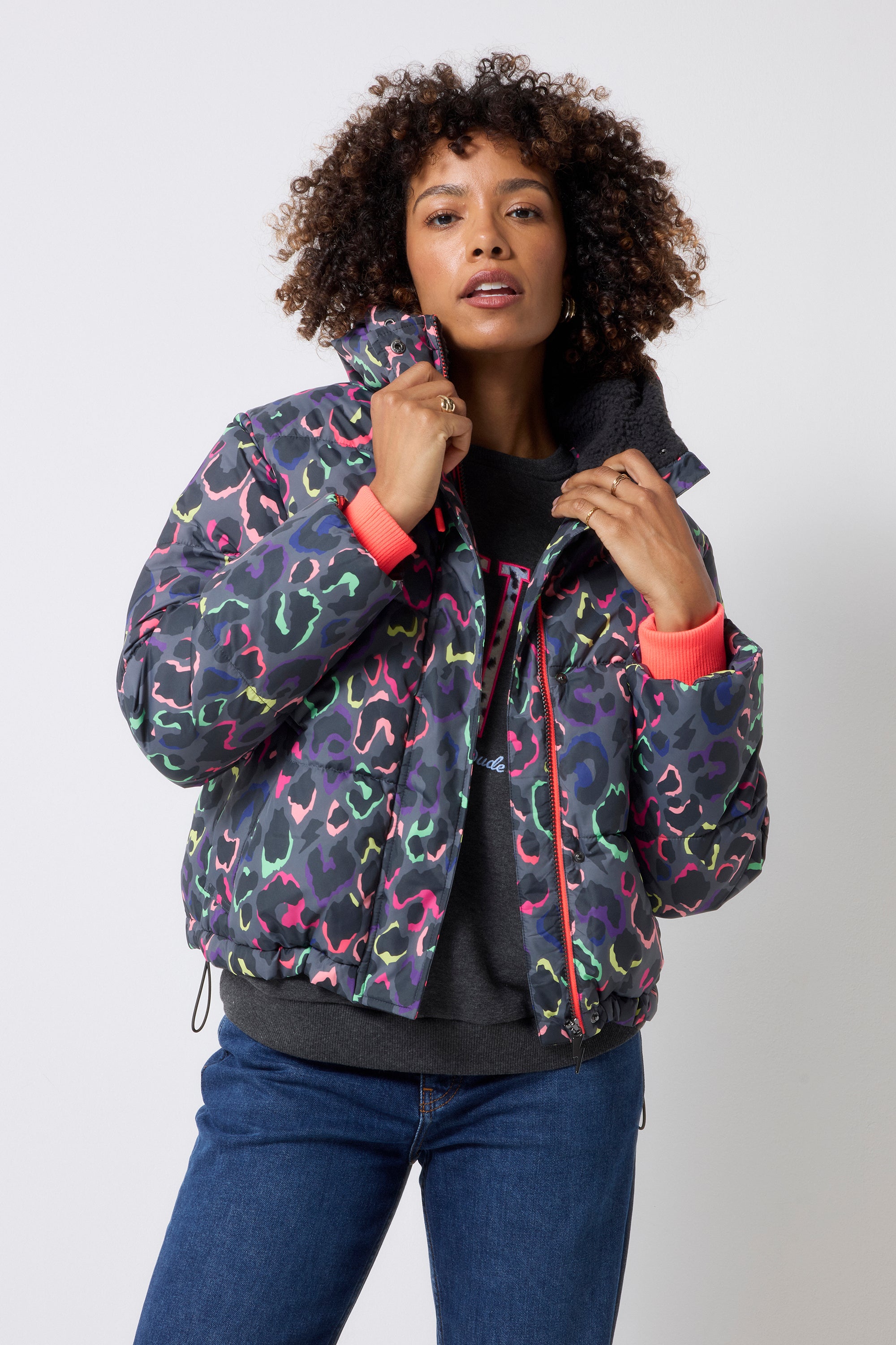 Scamp and Dude Grey with Rainbow Shadow Leopard Short Puffer Coat | Model wearing blue jeans with a dark grey love sweatshirt and a grey rainbow leopard puffer coat.