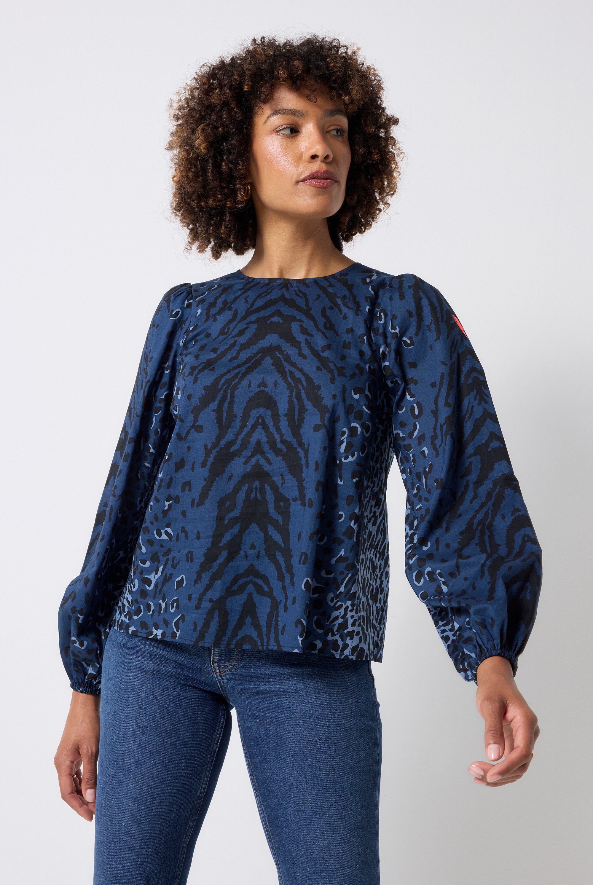 Scamp and Dude Navy with Black Zebra Blouson Sleeve Top | Model wearing a navy long sleeve zebra print top with dark blue jeans.