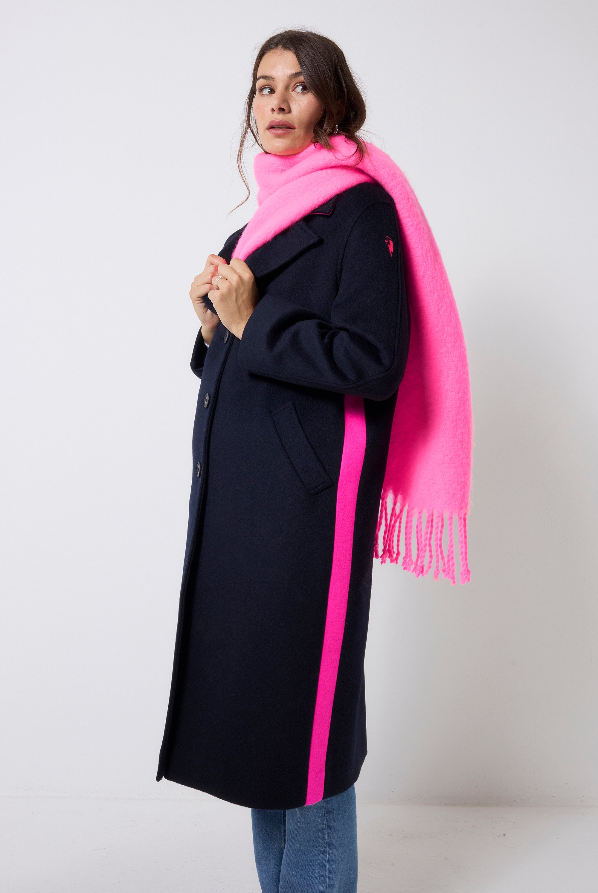 Scamp and Dude Neon Pink Fringe Scarf | Model wearing a navy wool blend coat with blue jeans and a neon pink fringe scarf.