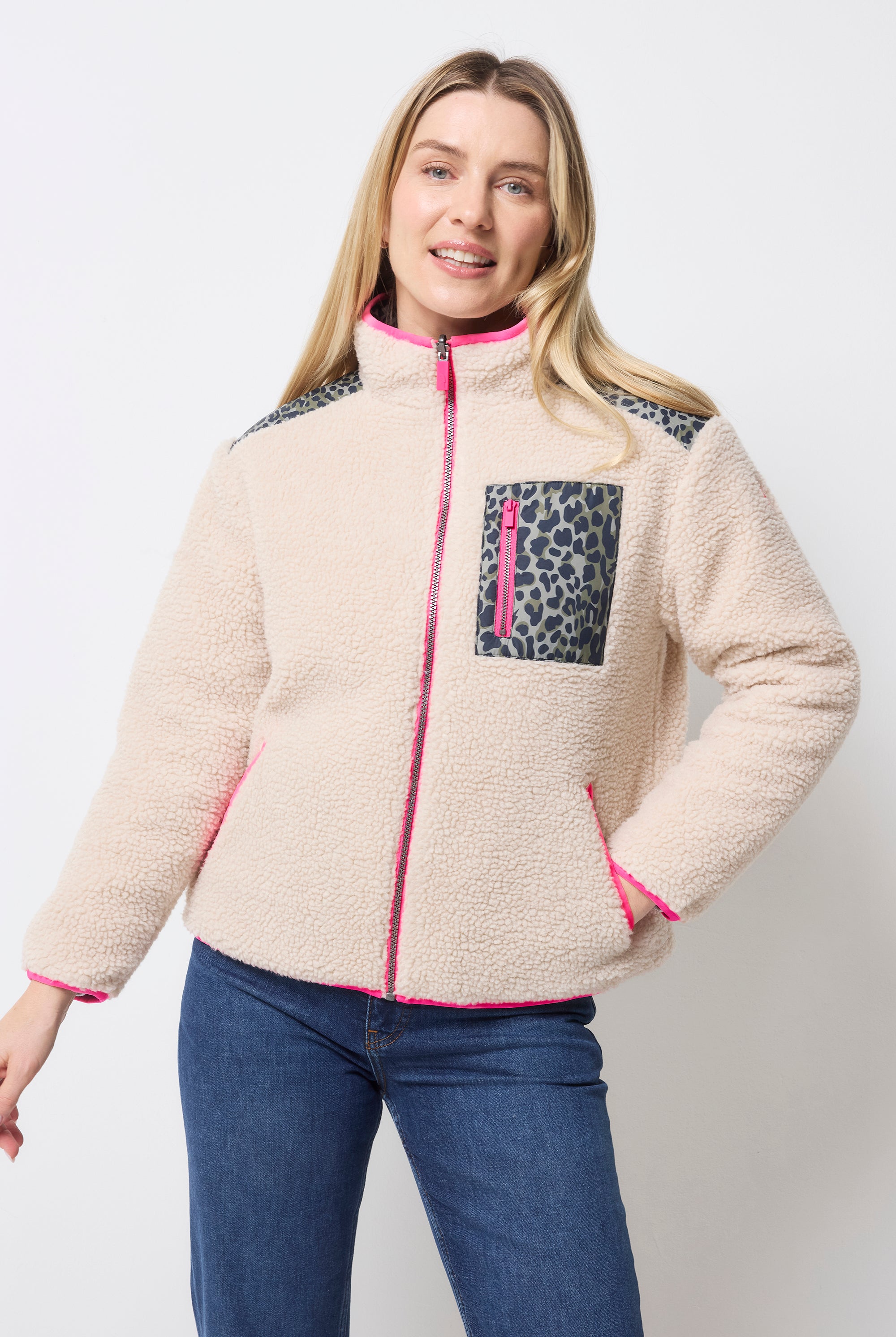 Scamp and Dude Khaki Wild Leopard Reversible Quilted Borg Coat | Model wearing a beige fleece jacket with leopard print pocket, paired with blue jeans.