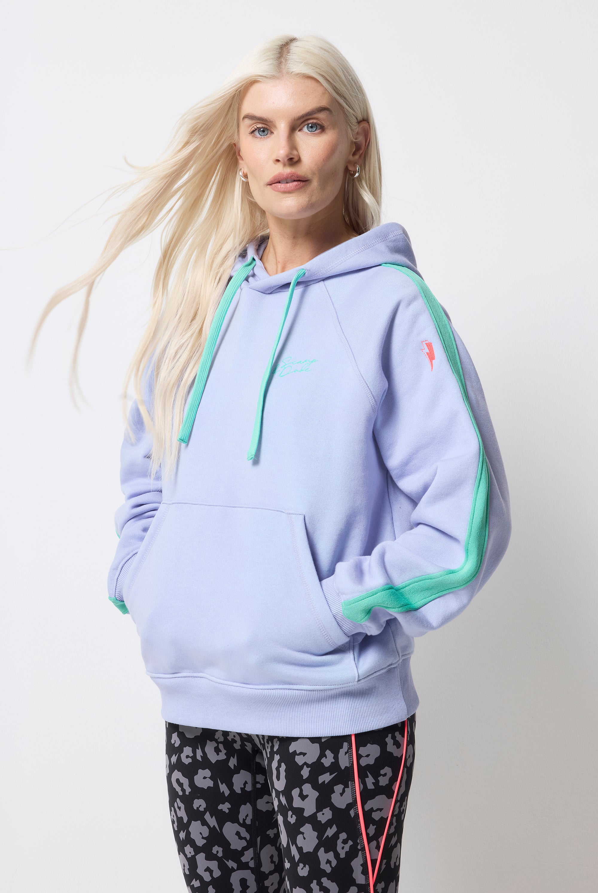 Scamp and Dude Blue with Turquoise Colourblock Relaxed Hoodie | Model wearing a blue hoodie with turquoise drawstrings and a colourblock stripe on the sleeve. Worn with black with grey leopard print leggings.
