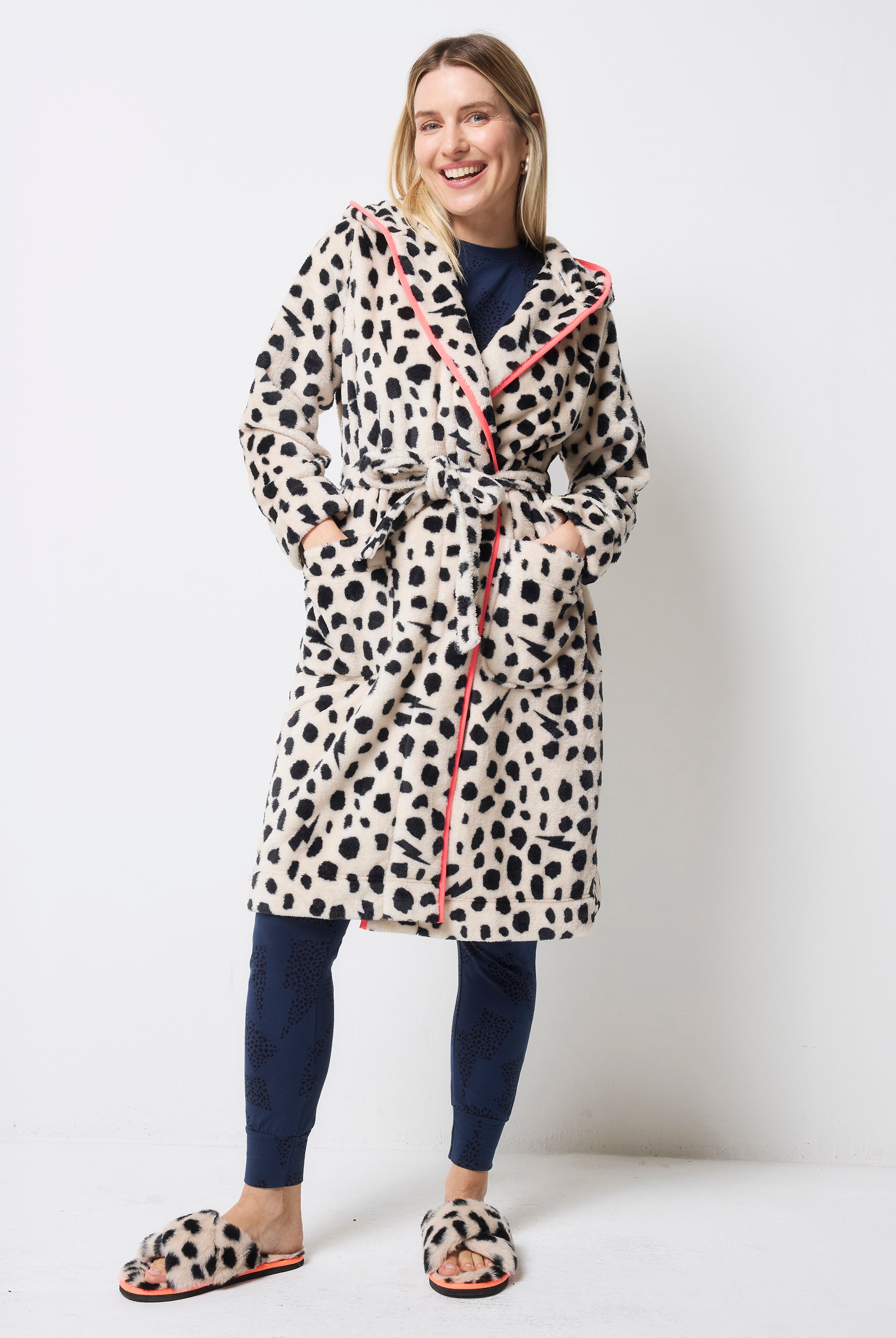 Scamp and Dude Cream with Black Cheetah Dressing Gown | Model wearing a navy pyjama set with a cream with black cheetah print dressing gown and matching slippers.