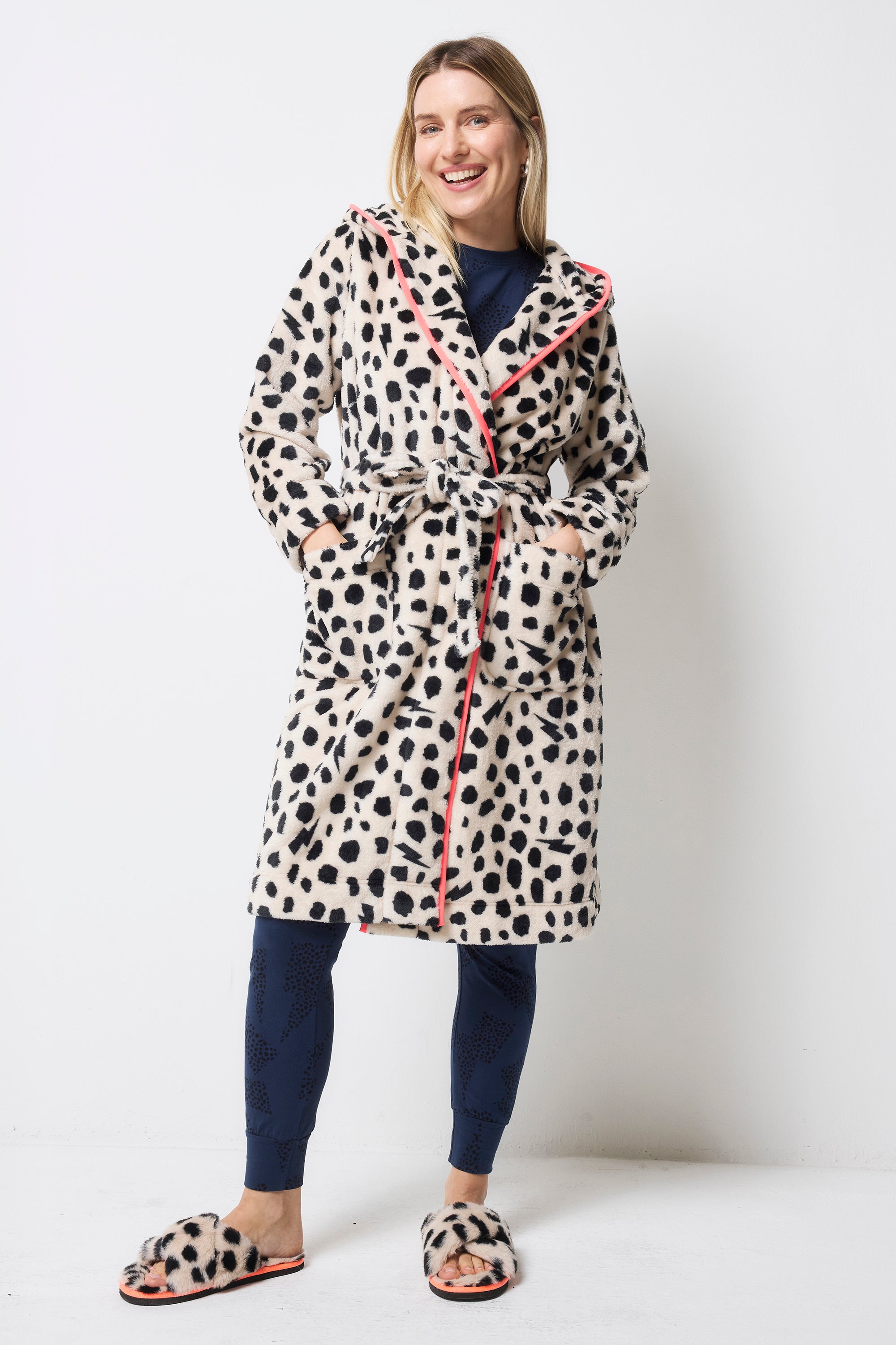 Scamp and Dude Cream with Black Cheetah Dressing Gown | Model wearing a navy pyjama set with a cream with black cheetah print dressing gown and matching slippers.