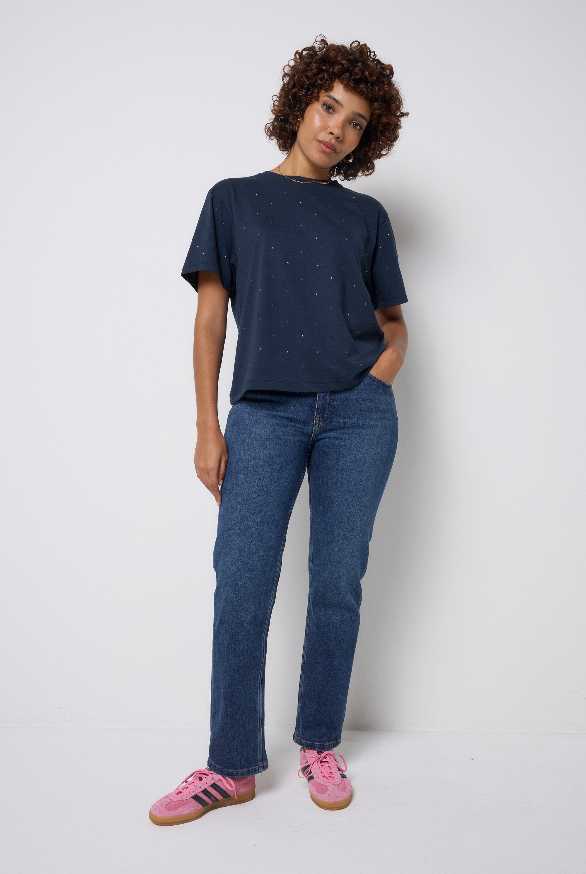 Scamp and Dude Navy Studded T-Shirt | Model wearing dark navy t-shirt with stud detail paired with dark blue jeans and pink trainers.
