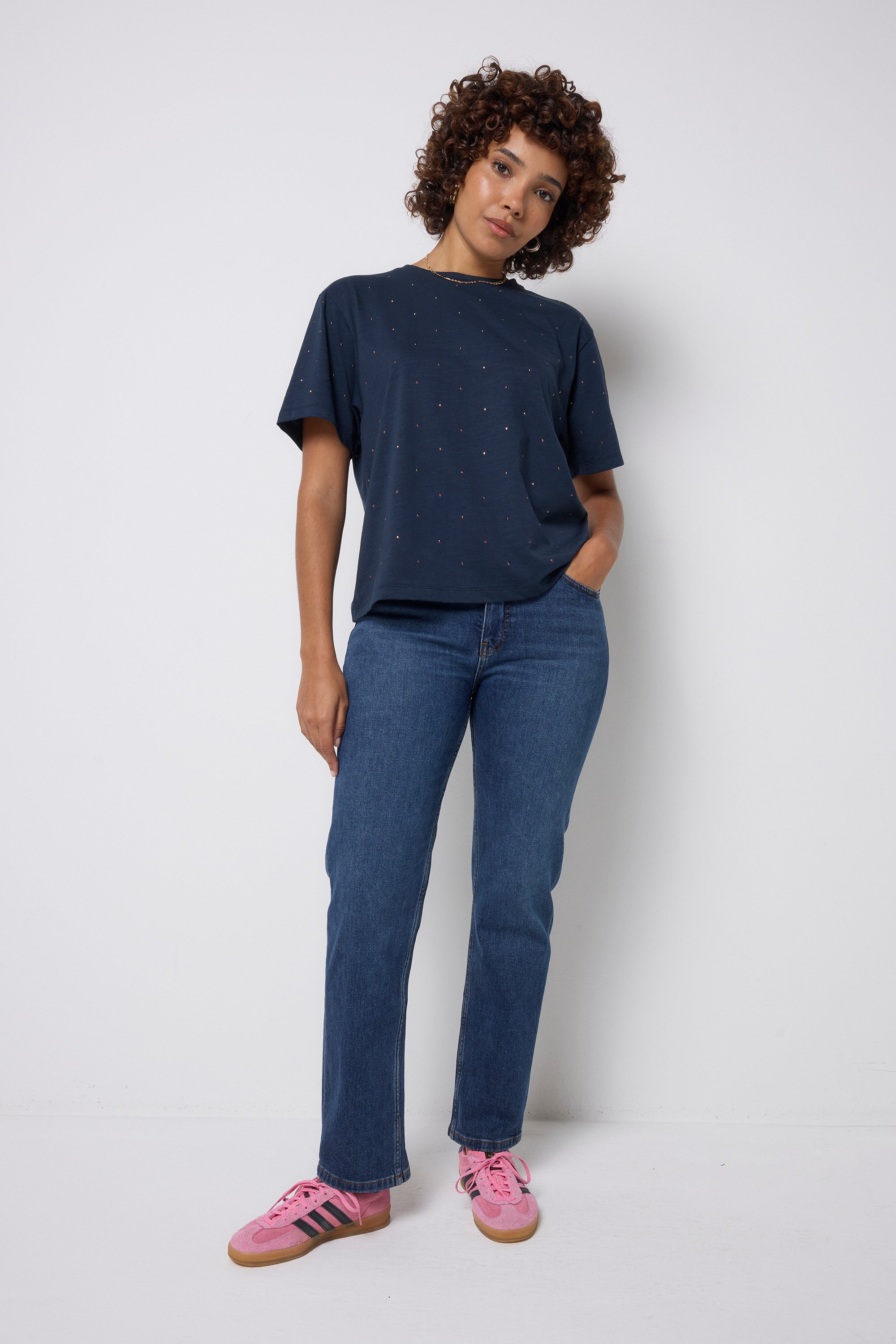 Scamp and Dude Navy Studded T-Shirt | Model wearing dark navy t-shirt with stud detail paired with dark blue jeans and pink trainers.
