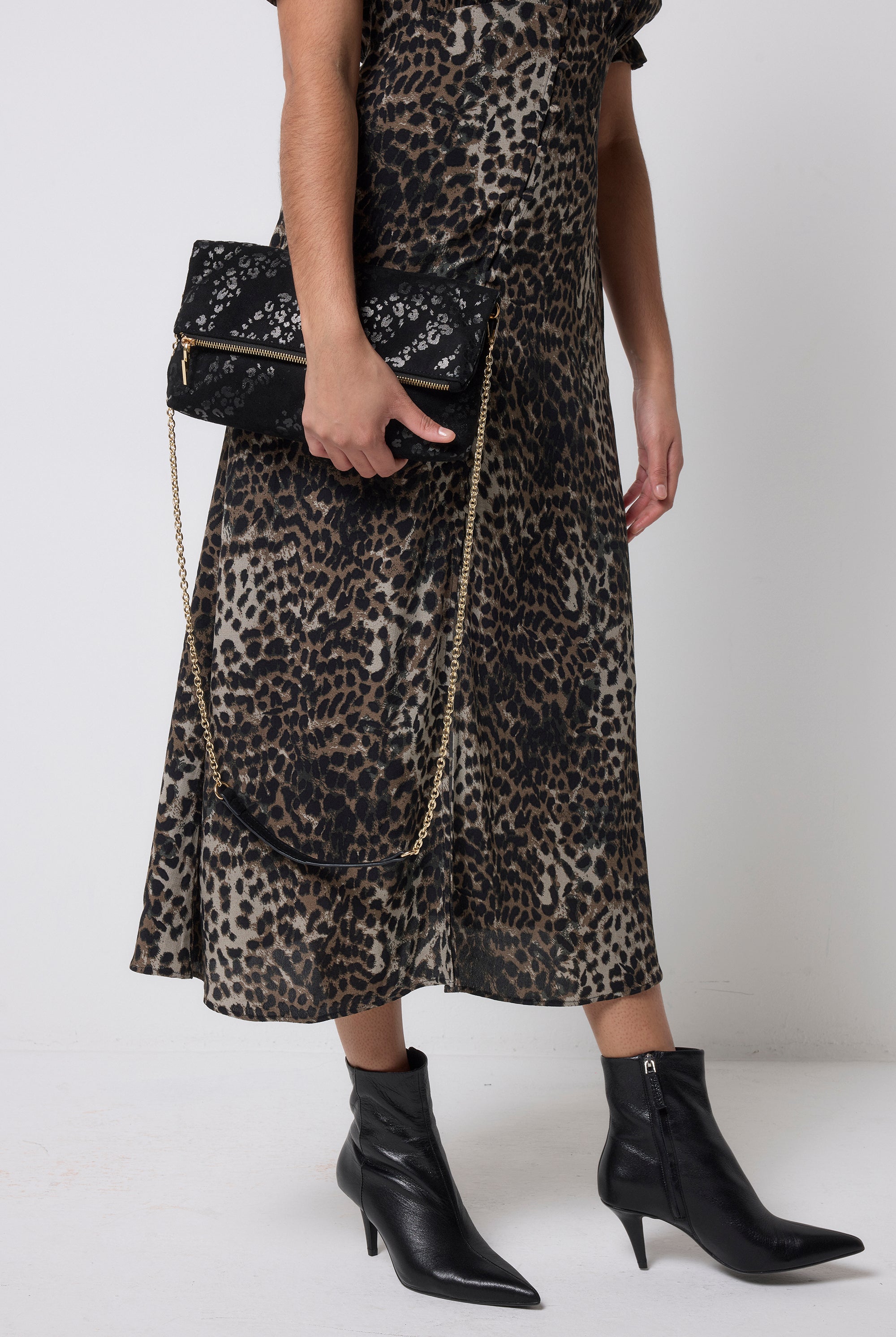 Scamp and Dude Black Leopard Faux Suede Cross Body Bag | Model holding a black leopard bag in a faux suede finish paired with a khaki cheetah print tea dress.
