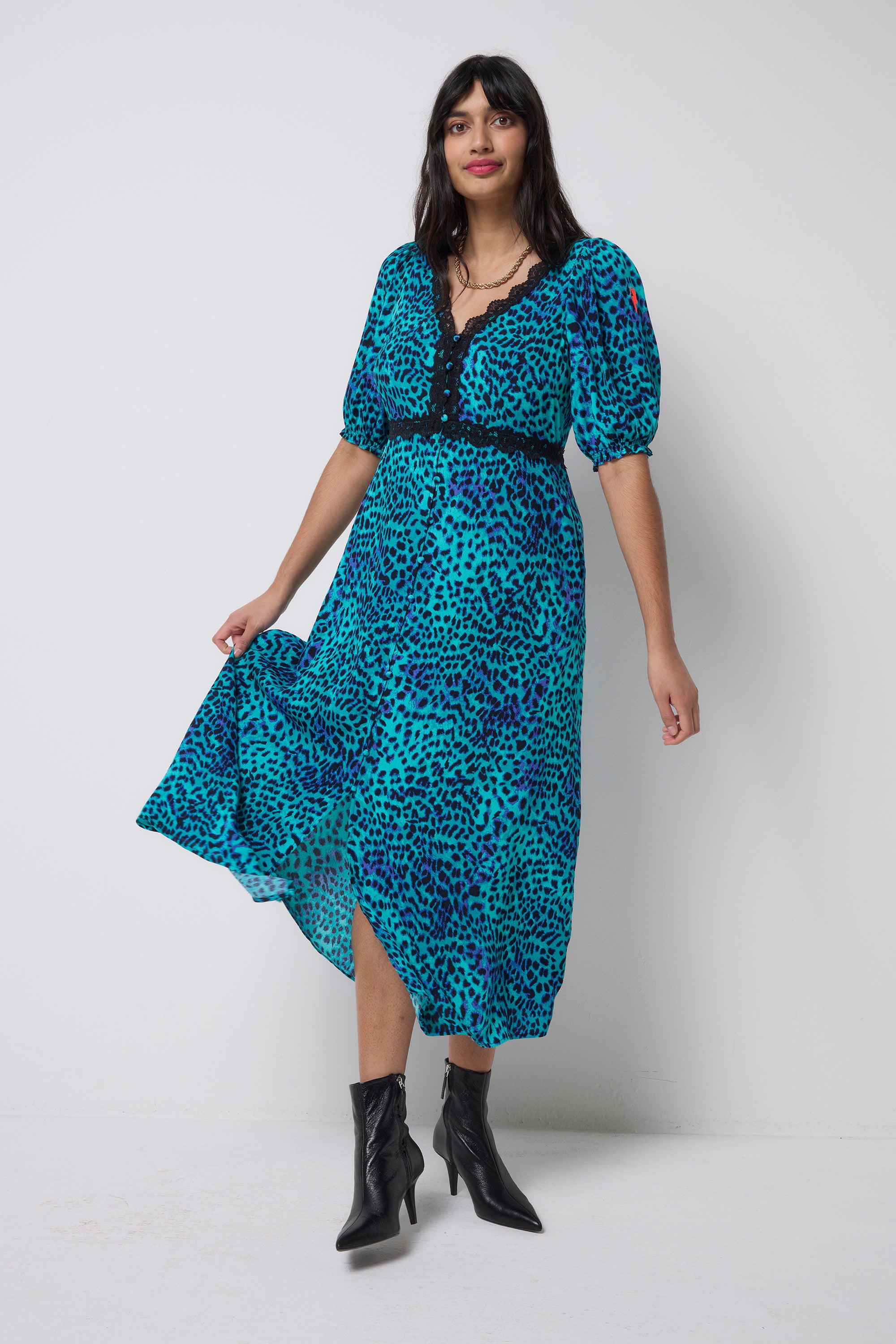 Scamp and Dude Turquoise with Blue Cheetah Lace Trim Puff Sleeve Midi Tea Dress | Model wearing a turquoise cheetah print dress with lace trim detail and black heeled boots.