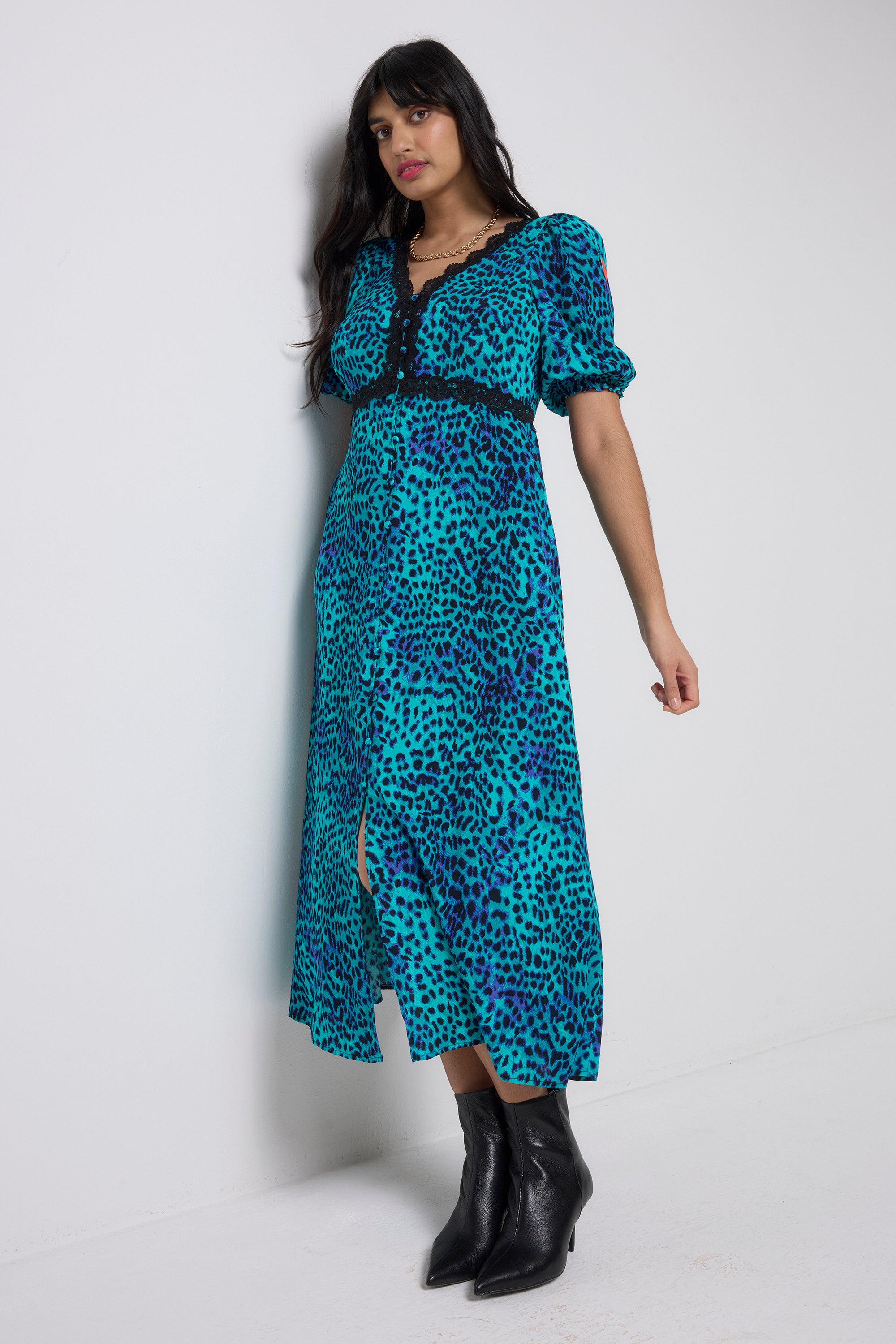 Scamp and Dude Turquoise with Blue Cheetah Lace Trim Puff Sleeve Midi Tea Dress | Model wearing a turquoise cheetah print dress with lace trim detail and black heeled boots.