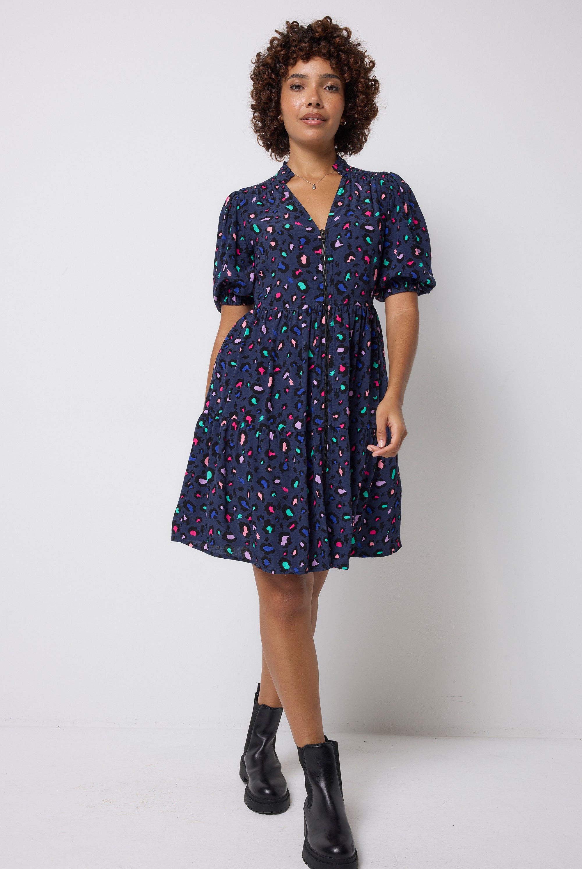 Scamp and Dude Navy with Rainbow Snow Leopard Zip Detail Tiered Short Dress | Model wearing dark navy short dress with zip front detail in a rainbow snow leopard print. Worn with black boots.