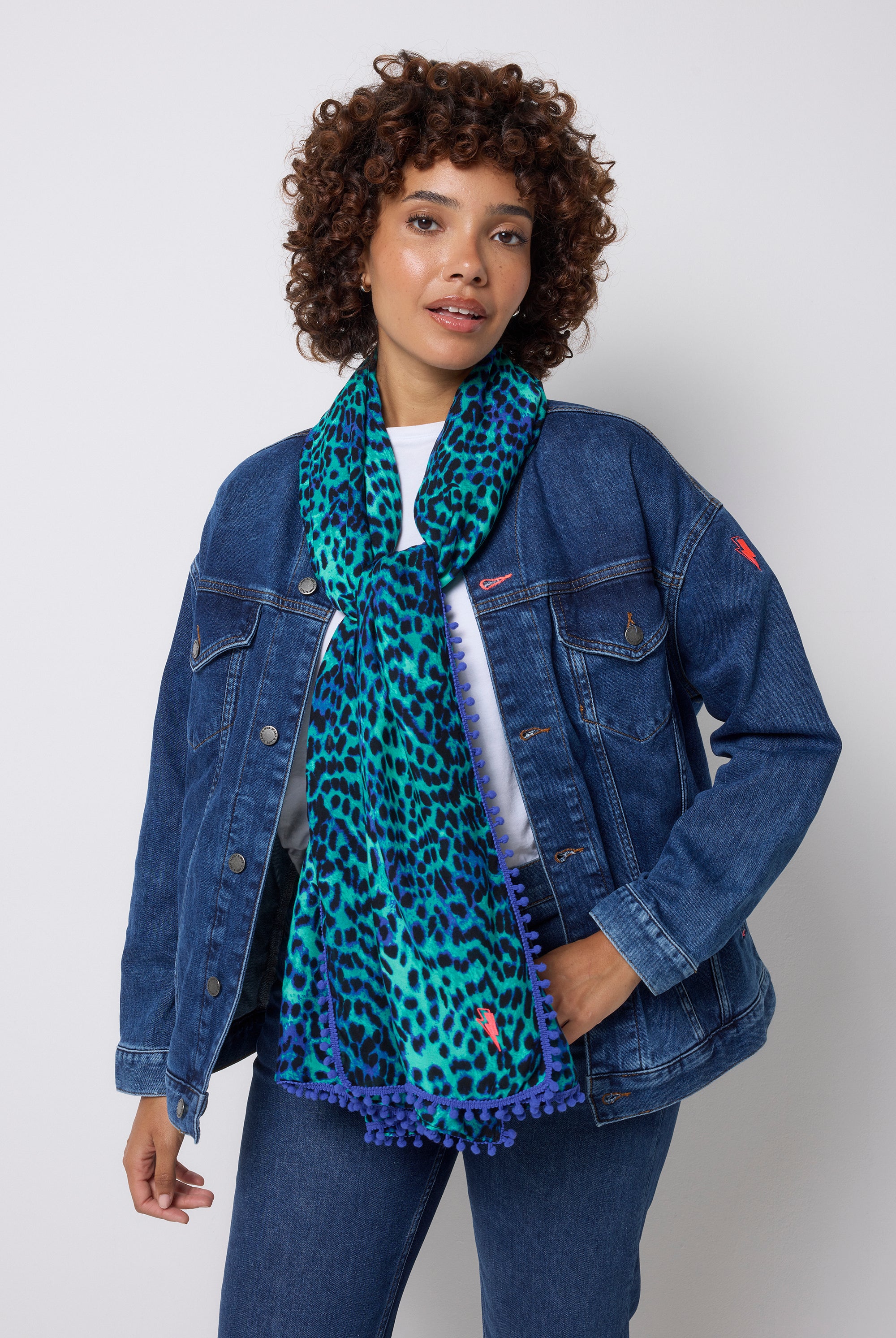 Scamp & Dude Turquoise with Blue Cheetah Charity Super Scarf | Model wearing a blue denim jacket and a turquoise cheetah print scarf against a white background.