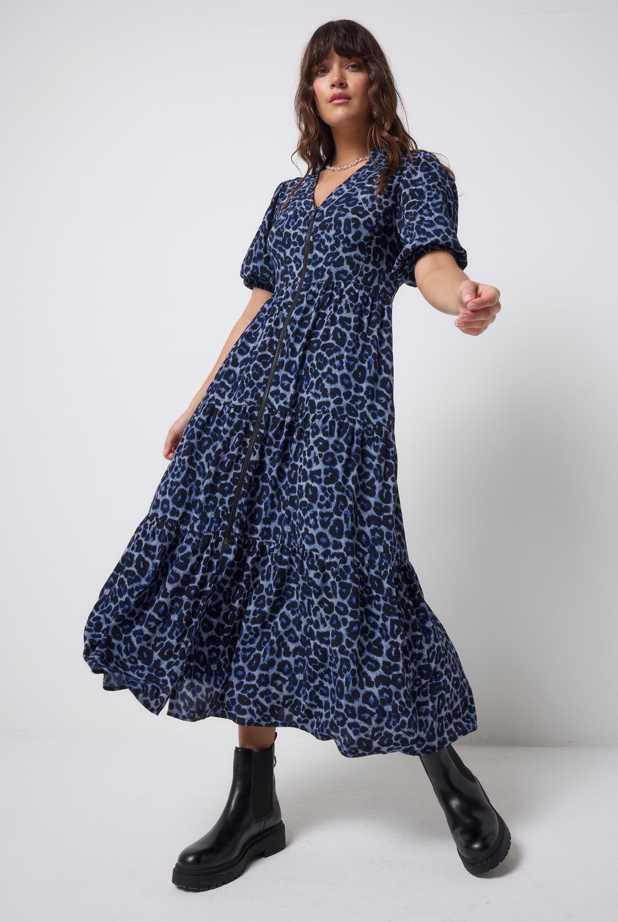 Scamp & Dude Navy Jaguar Shirred Zip Detail Midi Dress | Model wearing a blue zip front jaguar print dress with black boots on a white background