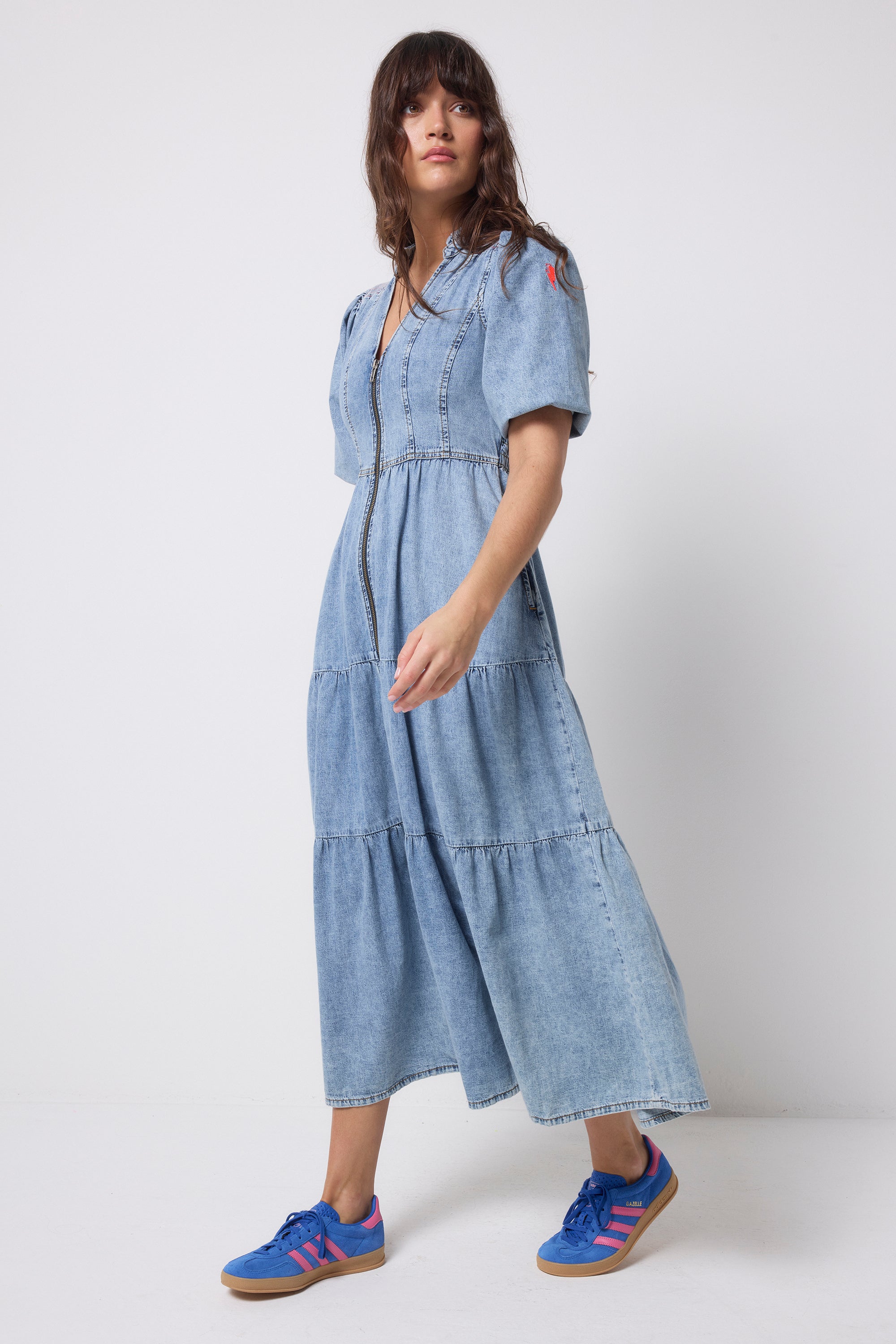 Scamp and Dude Pale Indigo Zip Detail Tiered Midi Denim Dress | Model wearing a pale wash denim dress with a zip through front and tiered skirt.